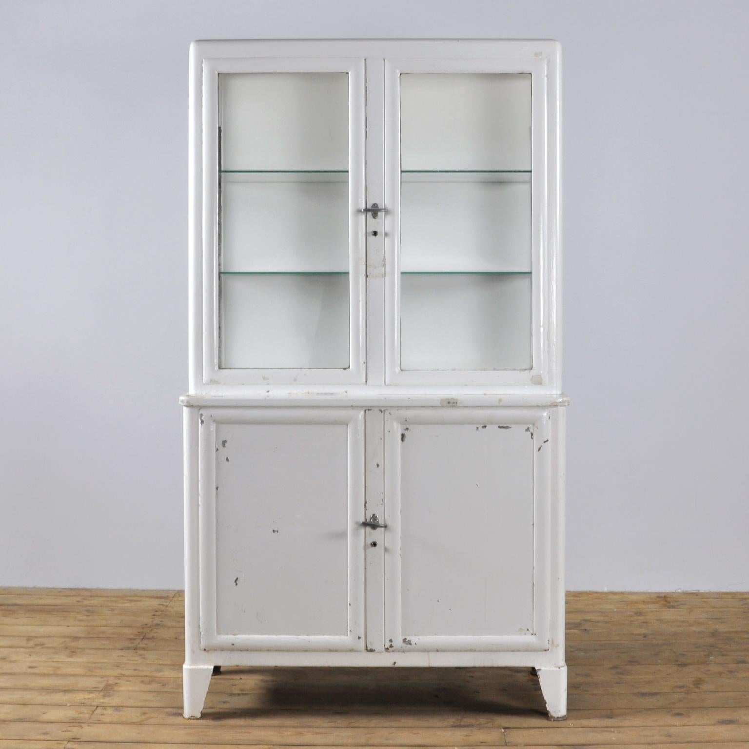 This former medicine cabinet was produced in the 1930s in Hungary and is made from thick iron and antique glass. It features two glass shelves.