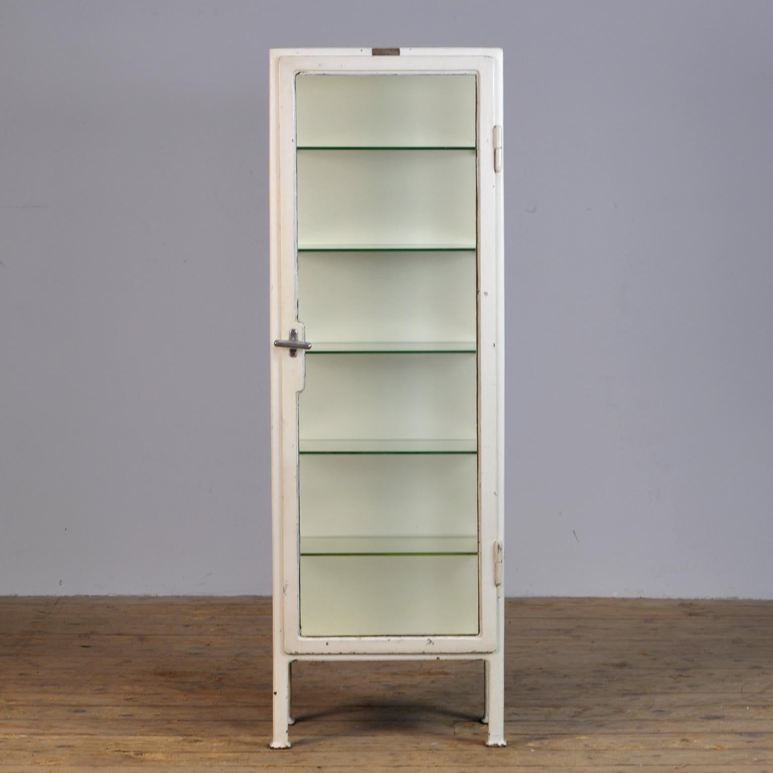 Unusual small medical cabinet from the 1930s with a label of the manufacturer above the door. The cabinet is produced in Hungary and is made of thick iron and the original antique glass. With the original glass plates, lock and handle.