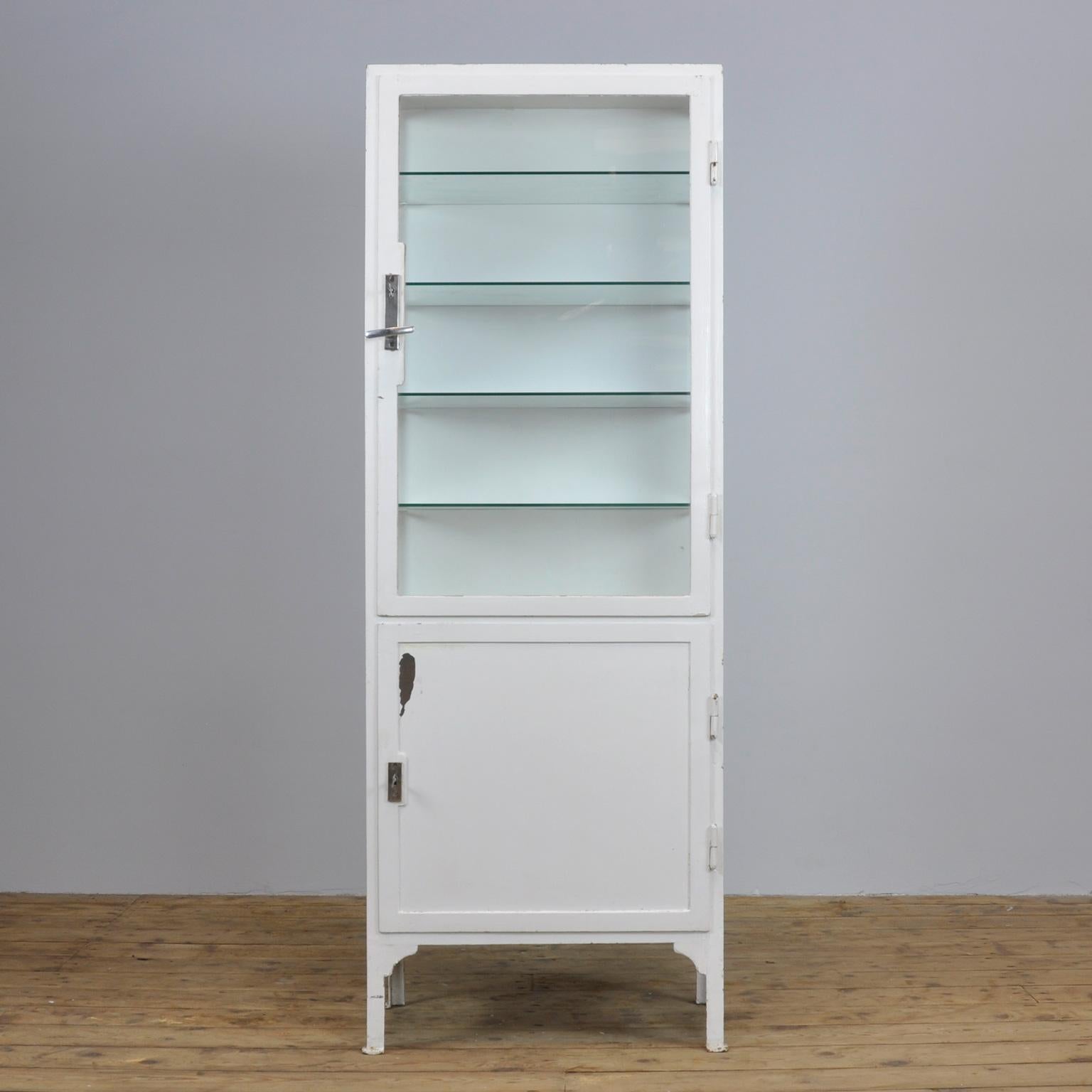 This former medicine cabinet was produced in the 1940s in Hungary and is made from thick iron and antique glass. It features four new glass shelves.