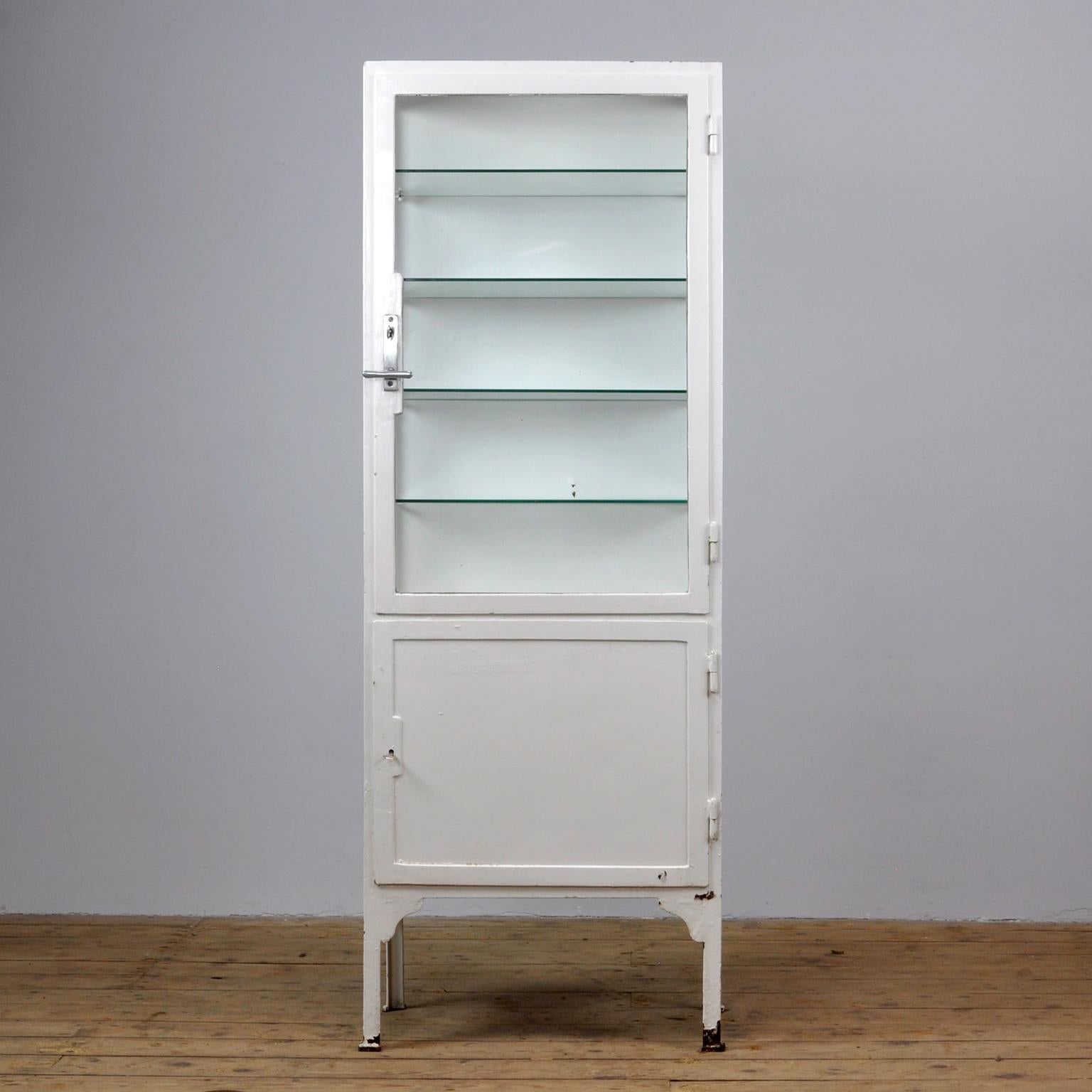 This former medicine cabinet was produced in the 1940s in Hungary and is made from thick iron and the original antique glass. With a very nice lock and handle on the top door. It features four new glass shelves.