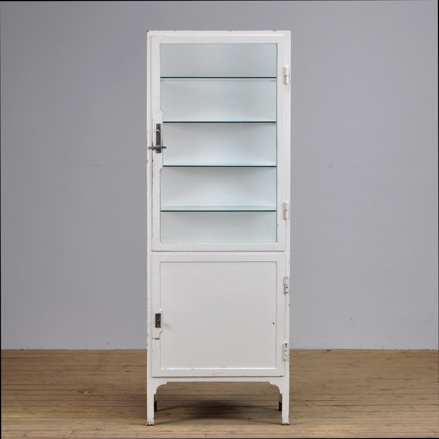 This former medicine cabinet was produced in the 1940s in Hungary and is made from thick iron and glass. With a very nice lock and handle on the top door. It features four new glass shelves.
   