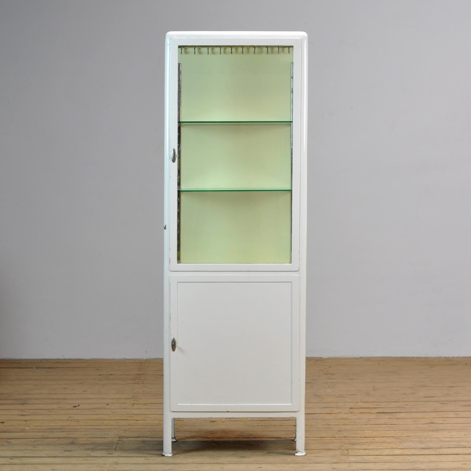 Medicine cabinet from the 1940s. The cabinet is produced in Germany and is made of iron and glass. With the original locks. In the upper part 2 new glass shelves and 10 (chrome-plated) clothes hooks.