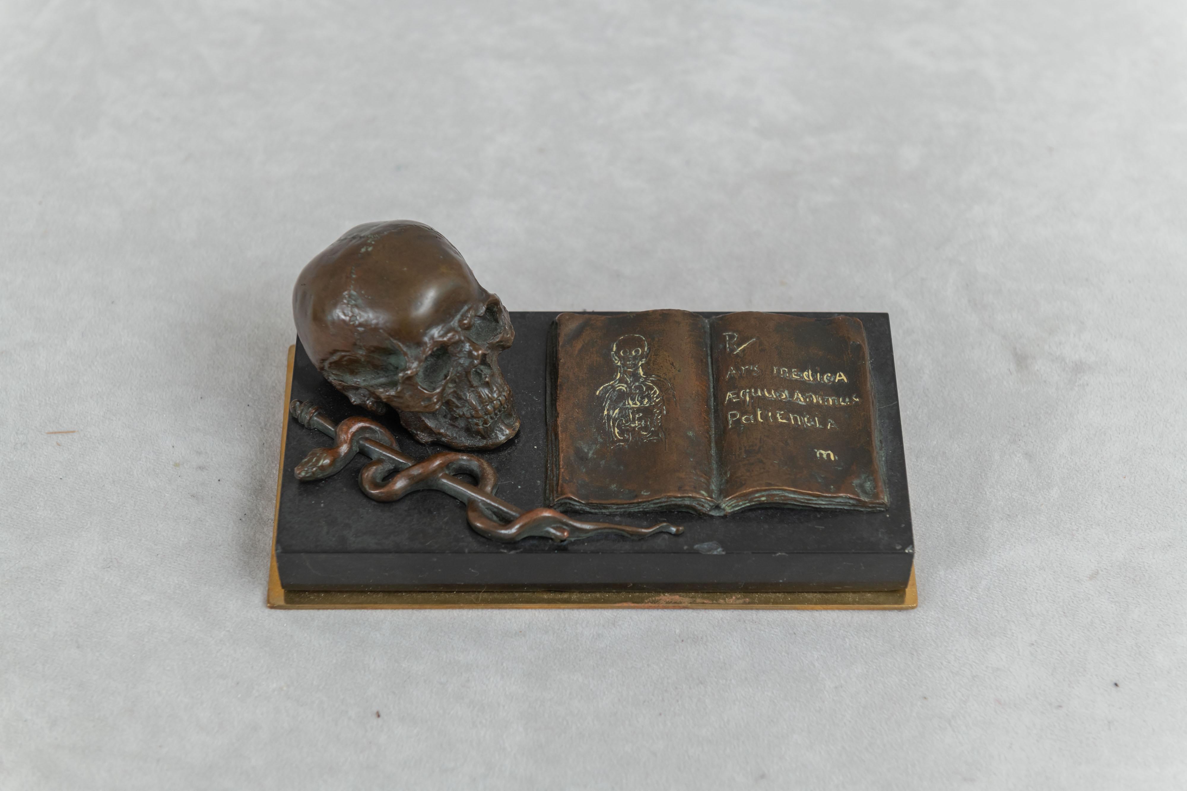 This most fascinating and rare themed bronze has all characteristics that a Medical Doctor would have a connection to. The Skull, the Caduceus (symbol of the medical profession) and the open book which has the word 