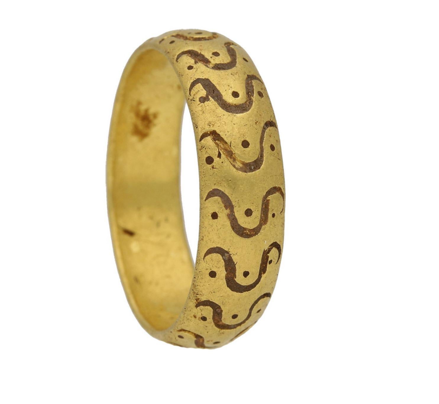Anello amuletico medievale. Un bracciale a forma di D in oro giallo, decorato con un motivo inciso di punti e linee sinuose a forma di omega, largo circa 5 mm. Testato in oro giallo, peso di circa 10 grammi, circa 14°-15° secolo ADS. 
