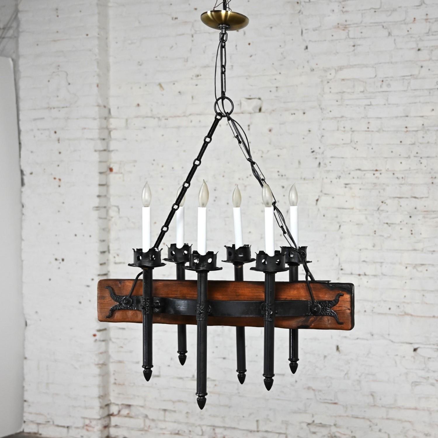 Awesome vintage Medieval Gothic or Spanish Revival iron & wood beam hanging light fixture with black iron chain, hammered iron details, candle posts, and a round brass canopy marked made in Mexico. Beautiful condition, keeping in mind that this is