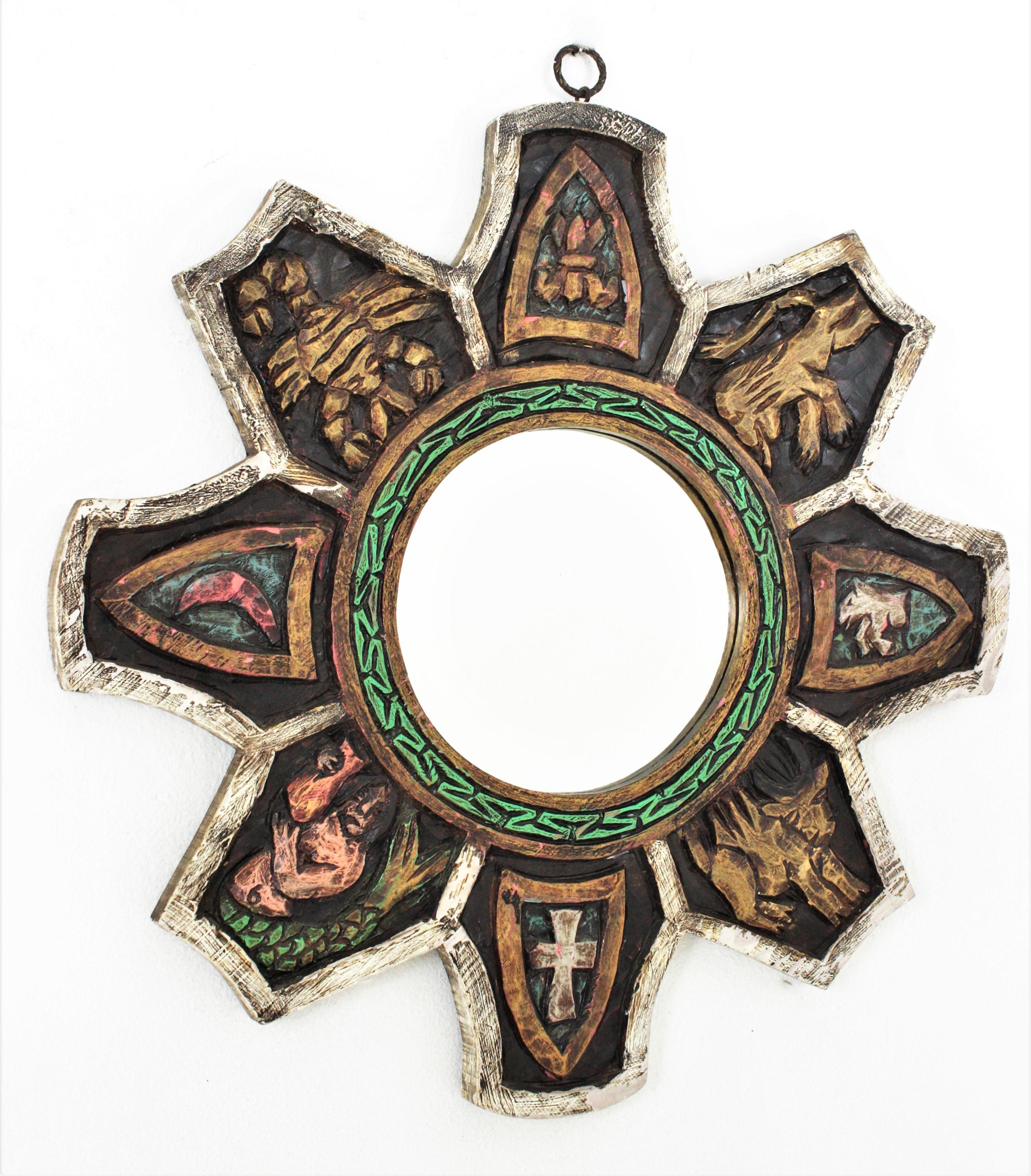 Medieval design sunburst starburst mirror in Carved Wood, Spain, 1950s-1960s
Handcrafted mirror with polychromy details, carved figures and coat of arms at the frame and green pattern surrounding the glass. 
Manufactured at the Midcentury Modern