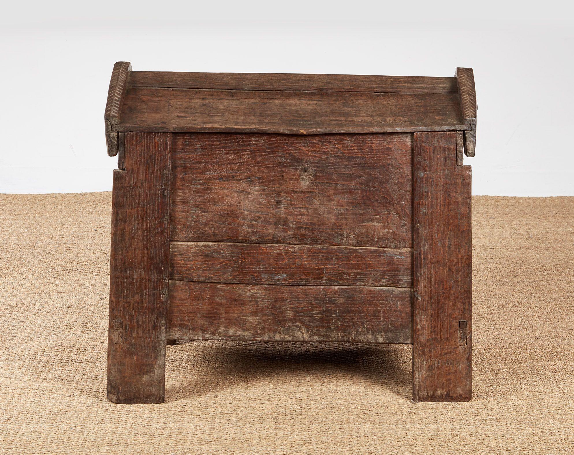 A very early oak chest with lovely silvery patina of heavy plank construction raised off the floor with integral legs extending the depth of the edges, and a hinged ridged top with thick shaped gable boards with chevron carving to the top surfaces. 