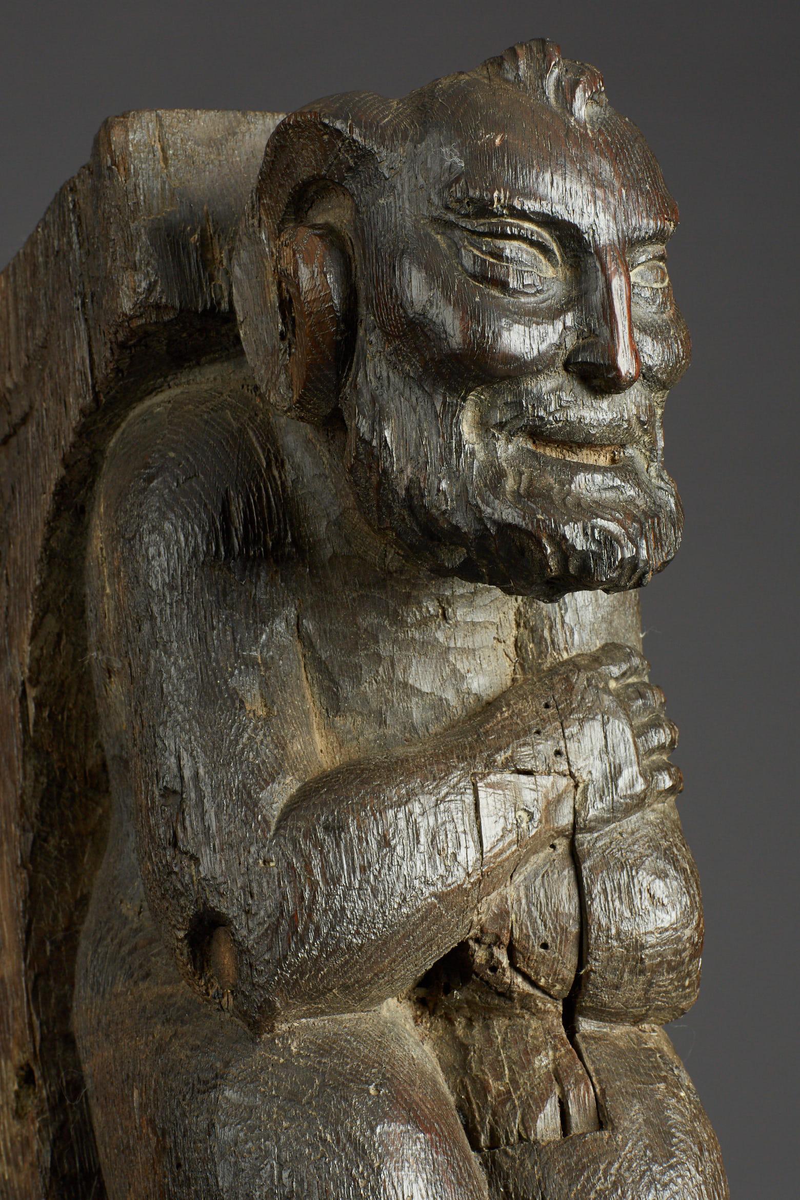 Mid-late 15th century oak corbel bracket of a satyr.

The bearded sylvan deity, half man and half goat, with crossed arms, goats legs and hooves. Originally a corbel or buttress bracket, with traces of original pegged tenons to front and rear.