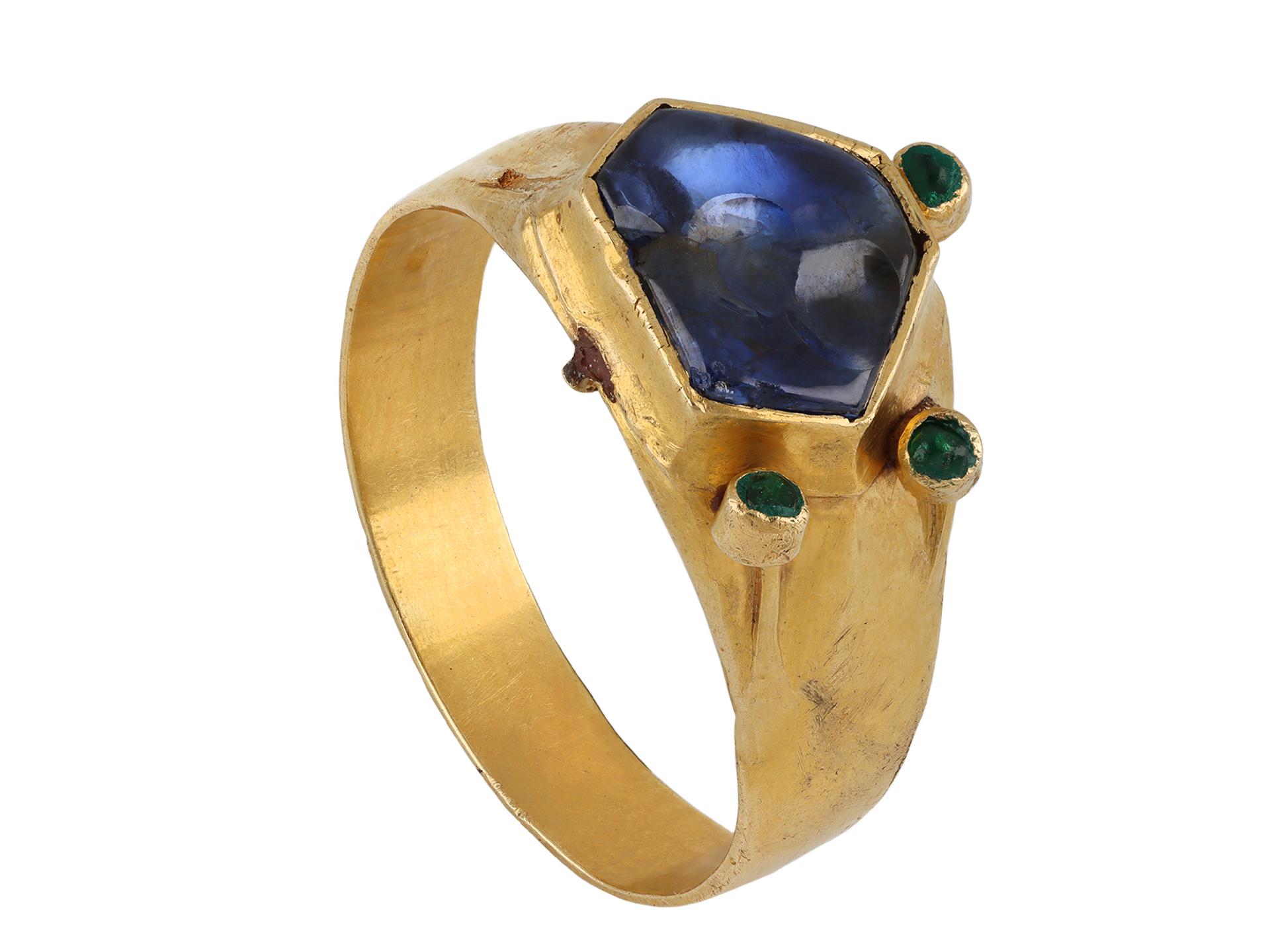 Medieval sapphire and emerald ring. Set to centre with a hexagonal cabochon natural sapphire in a closed back rubover setting with an approximate weight of 2.30 carats, further set with three round cabochon natural emeralds in closed back rubover