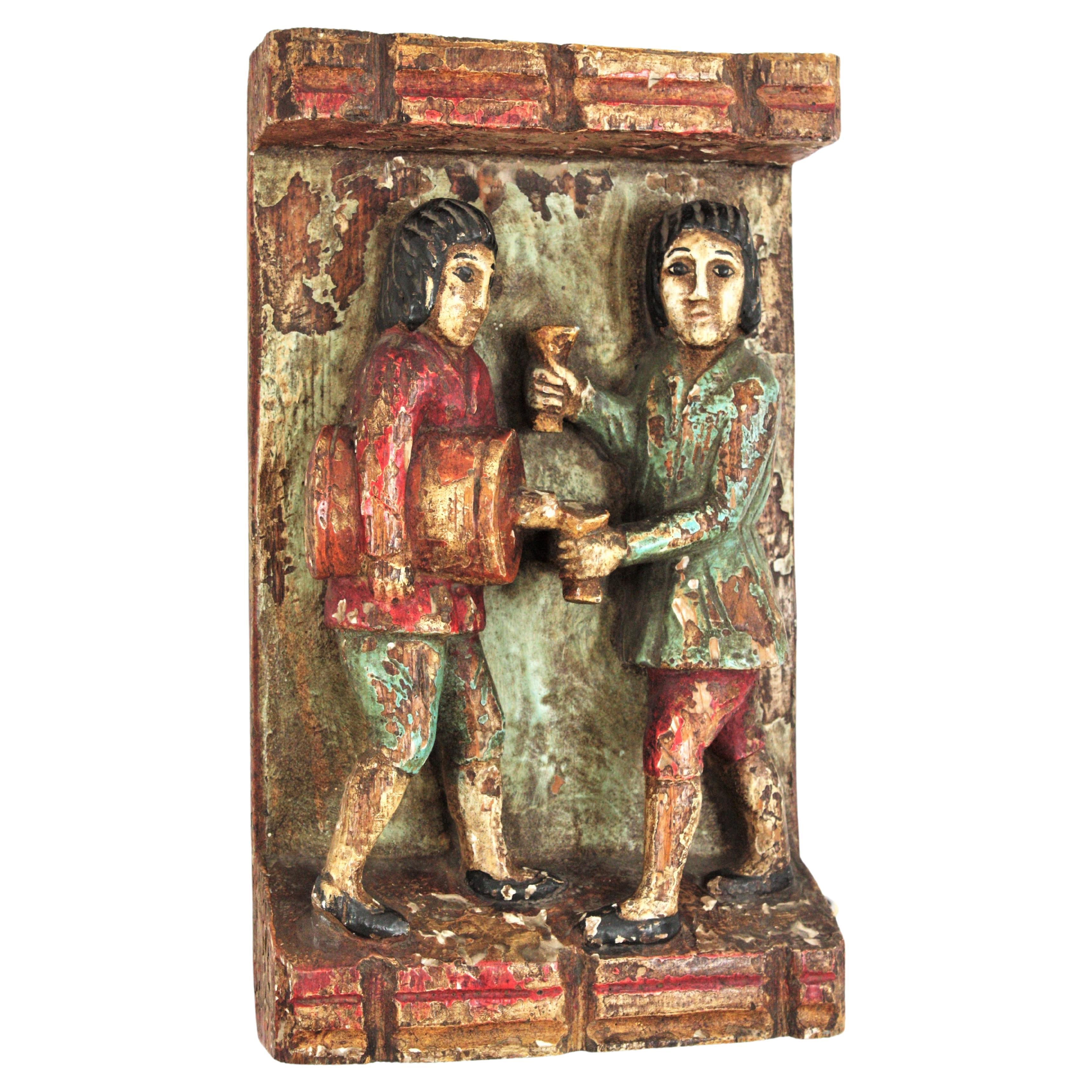 Mid-Century Modern Medieval Inspired Bas Relief Wall Decoration in Polychromed Carved Wood. Spain, 1950s.
Beautifully hand-carved bas relief depicting genre scene. Two standing men figures, one serving wine from a barrel, the other one hanging two
