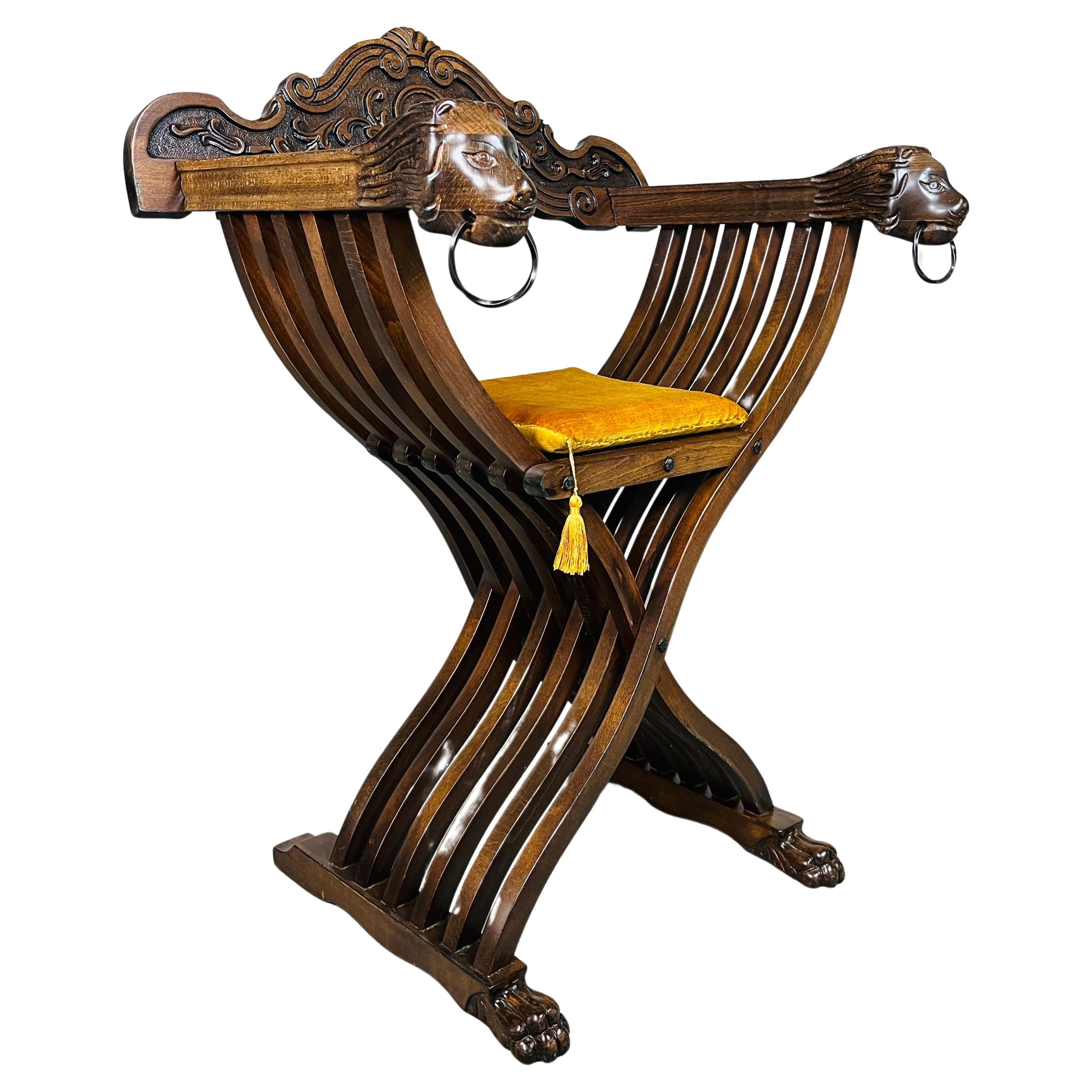 A beautiful Italian Savonarola x-base chair having detailed hand carved mahogany lions face armrests with lion claw feet from the early 20th century. The chair collapses down for easy storage by lifting the backrest off and pulling up on the seat.