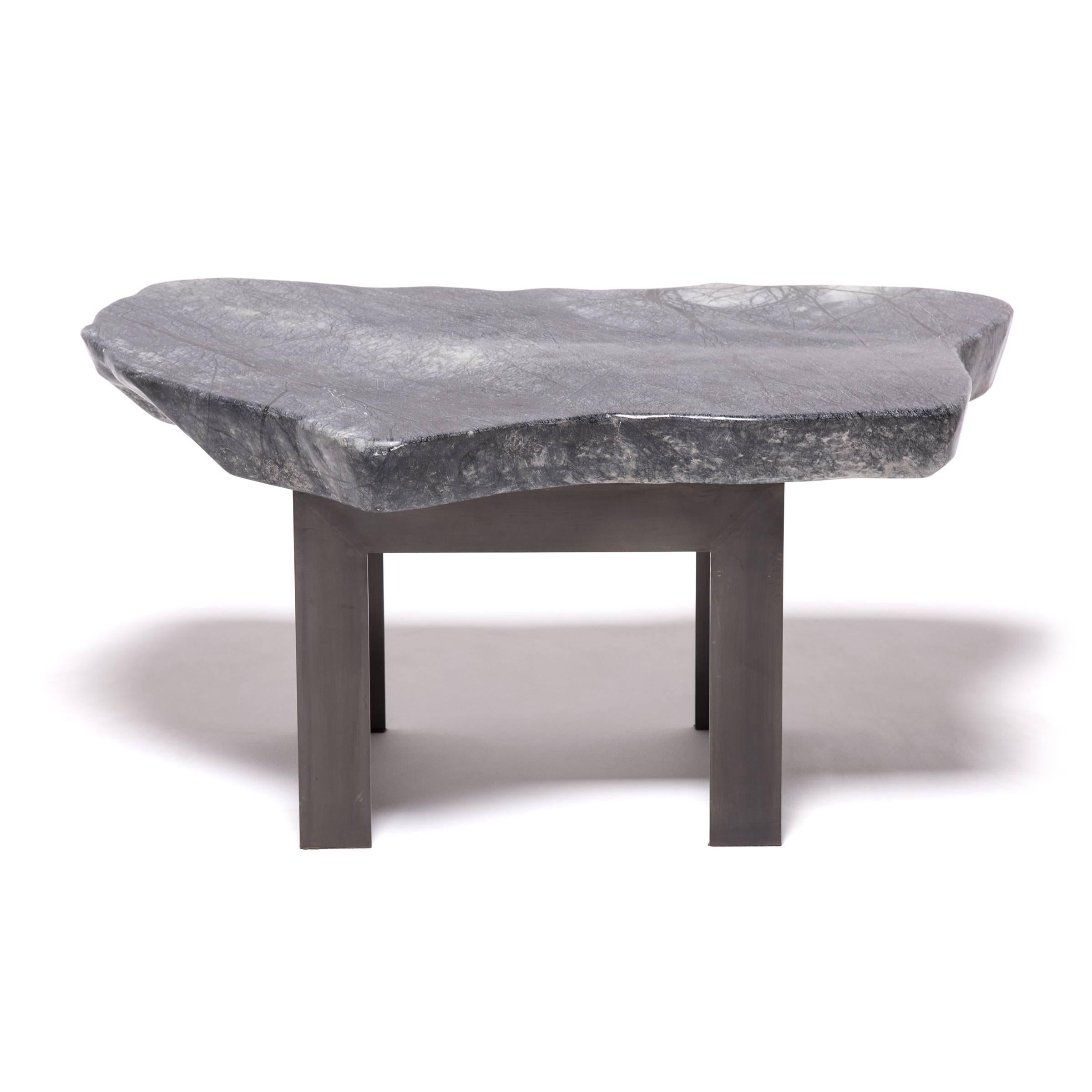 Prized by ancient scholars, meditation stones provided inspiration for poetry, painted landscapes, or brushed calligraphy. Supported by a custom Parson’s-style steel base, this organically shaped stone top is marked by spidery veins of black that