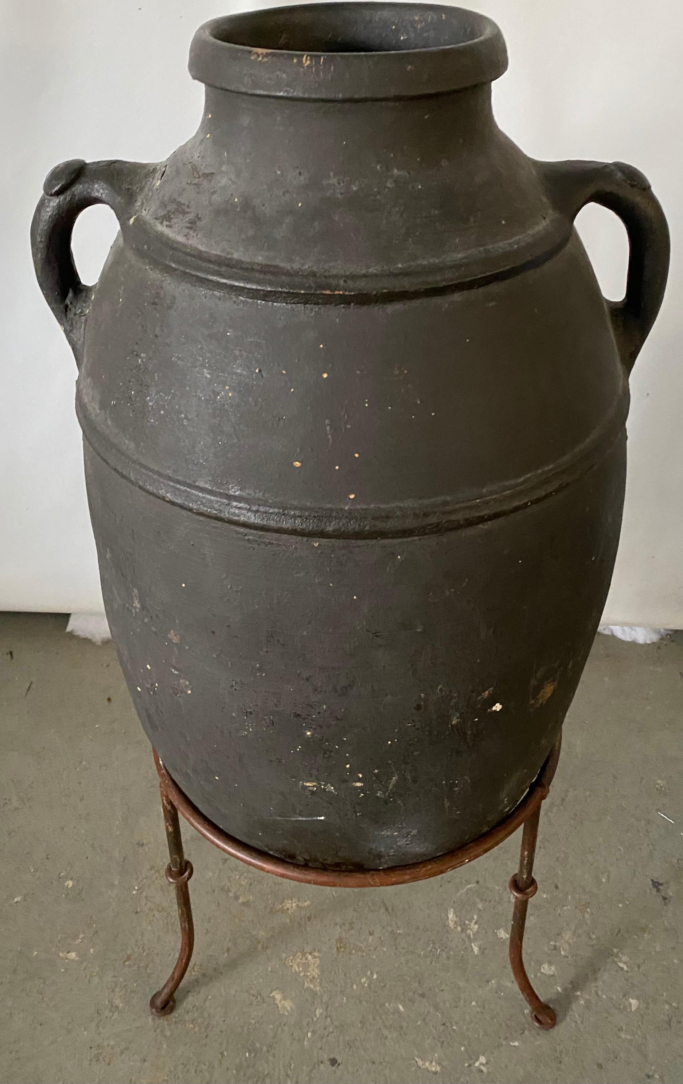 A unique piece of handmade glazed terracotta olive oil storage jar on a tripod metal Stand much like the Biot style. This type of jars were typically used for olive oil and exported around the entire Mediterranean region. It would look great outside