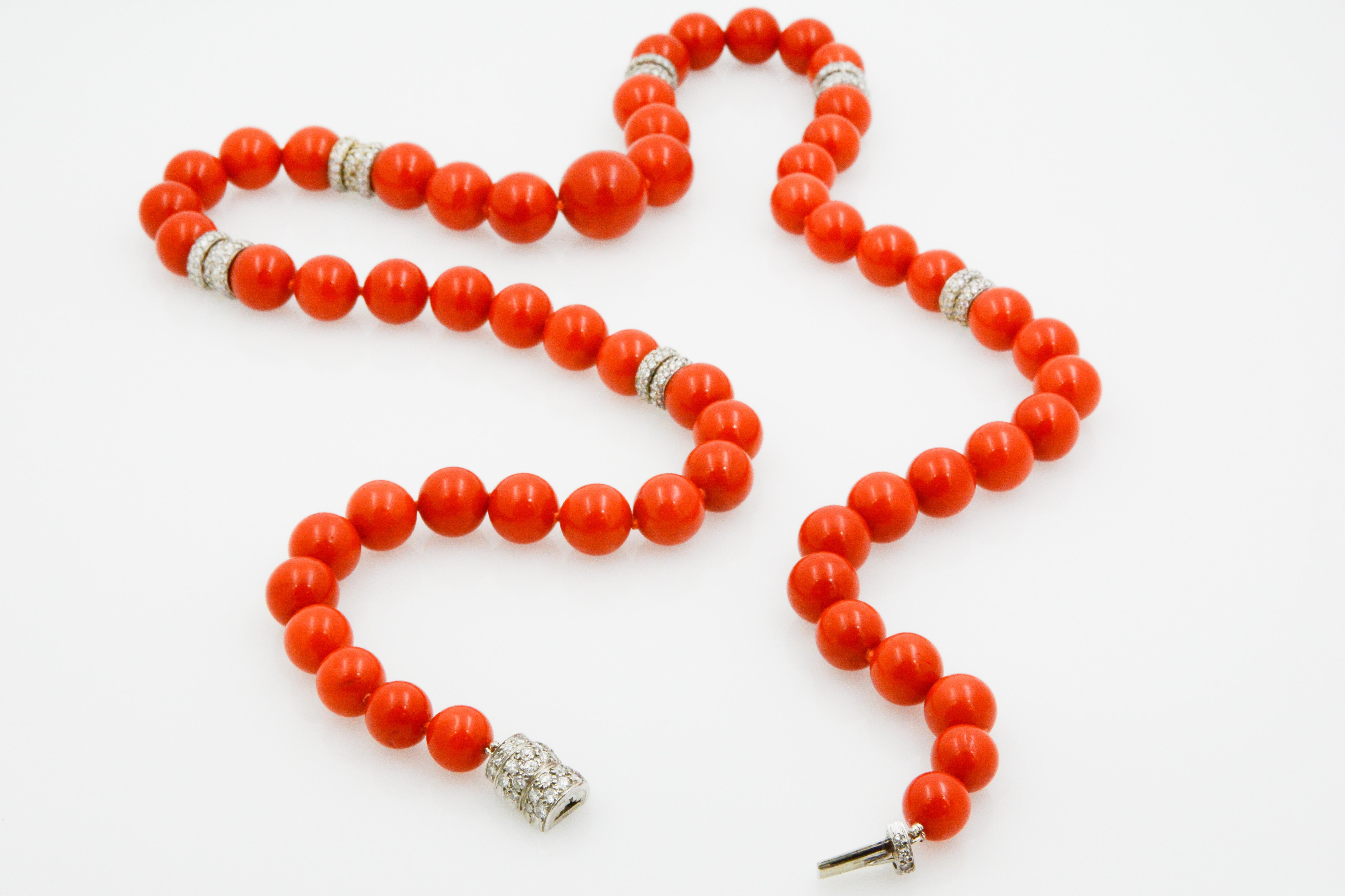 This stately necklace has a strand of 59 graduated Mediterranean coral beads that each measures at 15.5 x 8mm. The necklace has splashes of six 14 karat white gold pave rondelles decorated with 34 round brilliant diamonds, weighing a total of 2.16