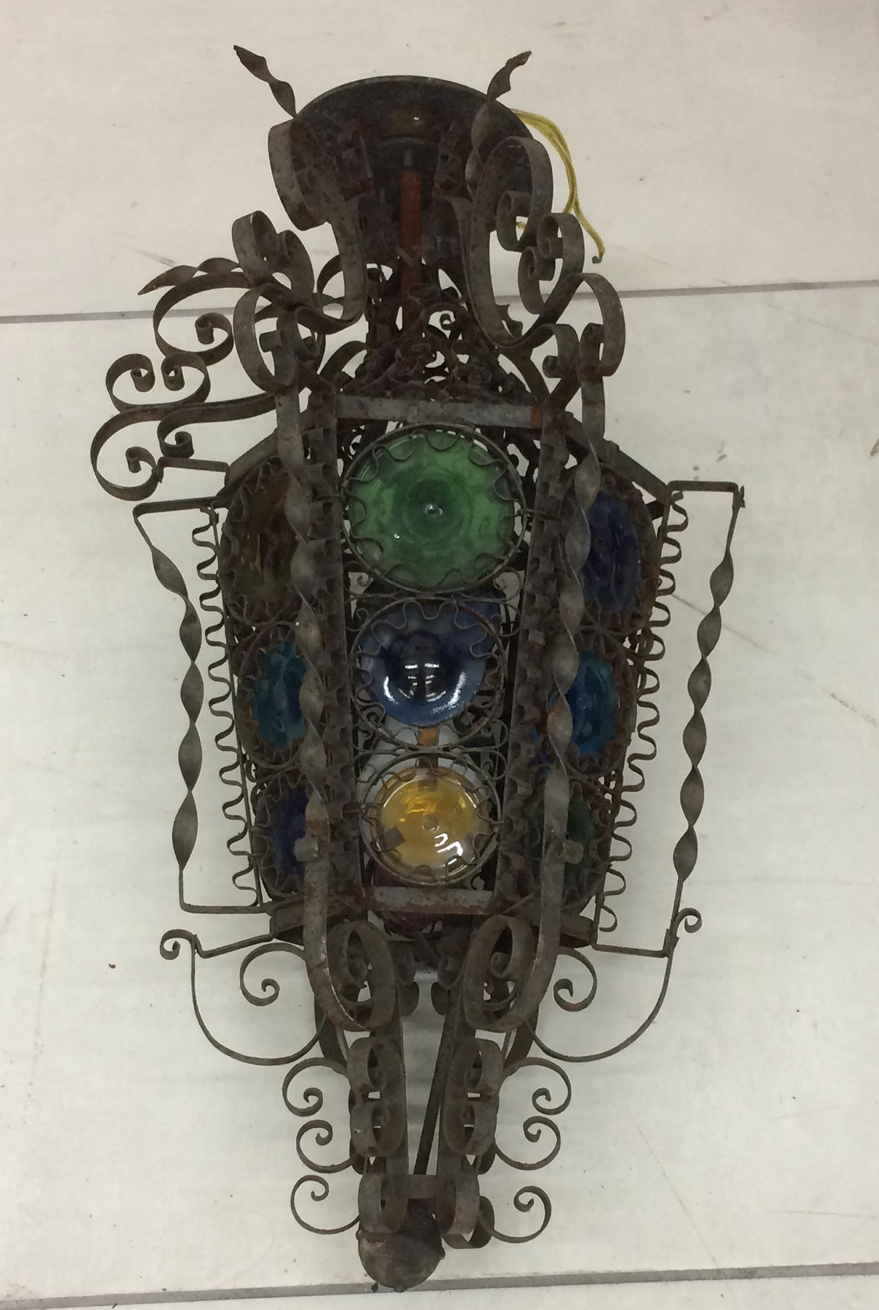 Flush mount pendant style light fixture. Hand wrought iron with round multi colored glass shade and iron curly cues. Spanish colonial style probably made in Mexico in the late 19th century. Originally designed for a candle has been electrified for