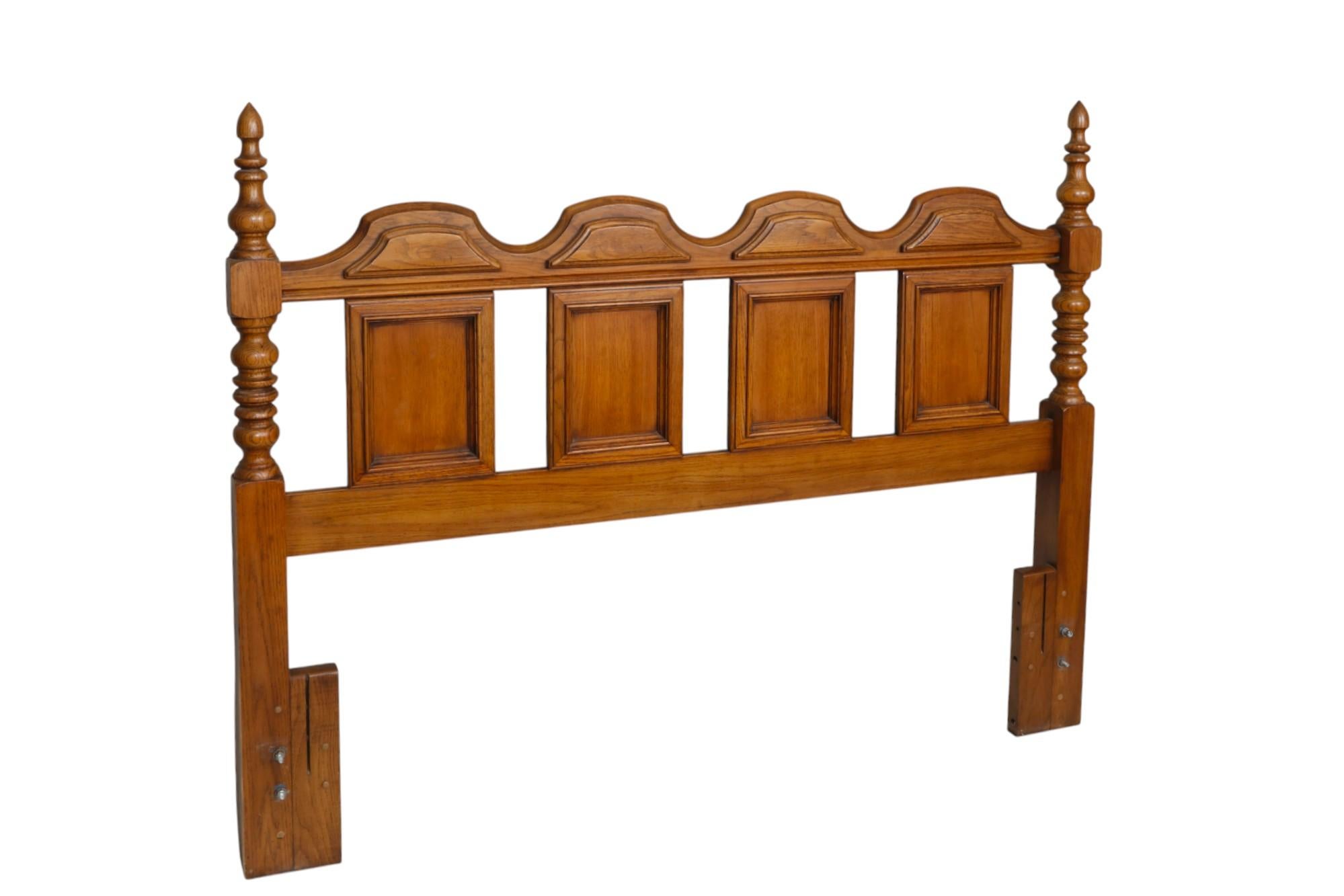 A Mediterranean style queen size headboard attributed to Thomasville of North Carolina. Richly turned posts with simple acorn shaped finials frame four rectangular inset panels with beveled edges. The crest rail is decorated with four raised paneled