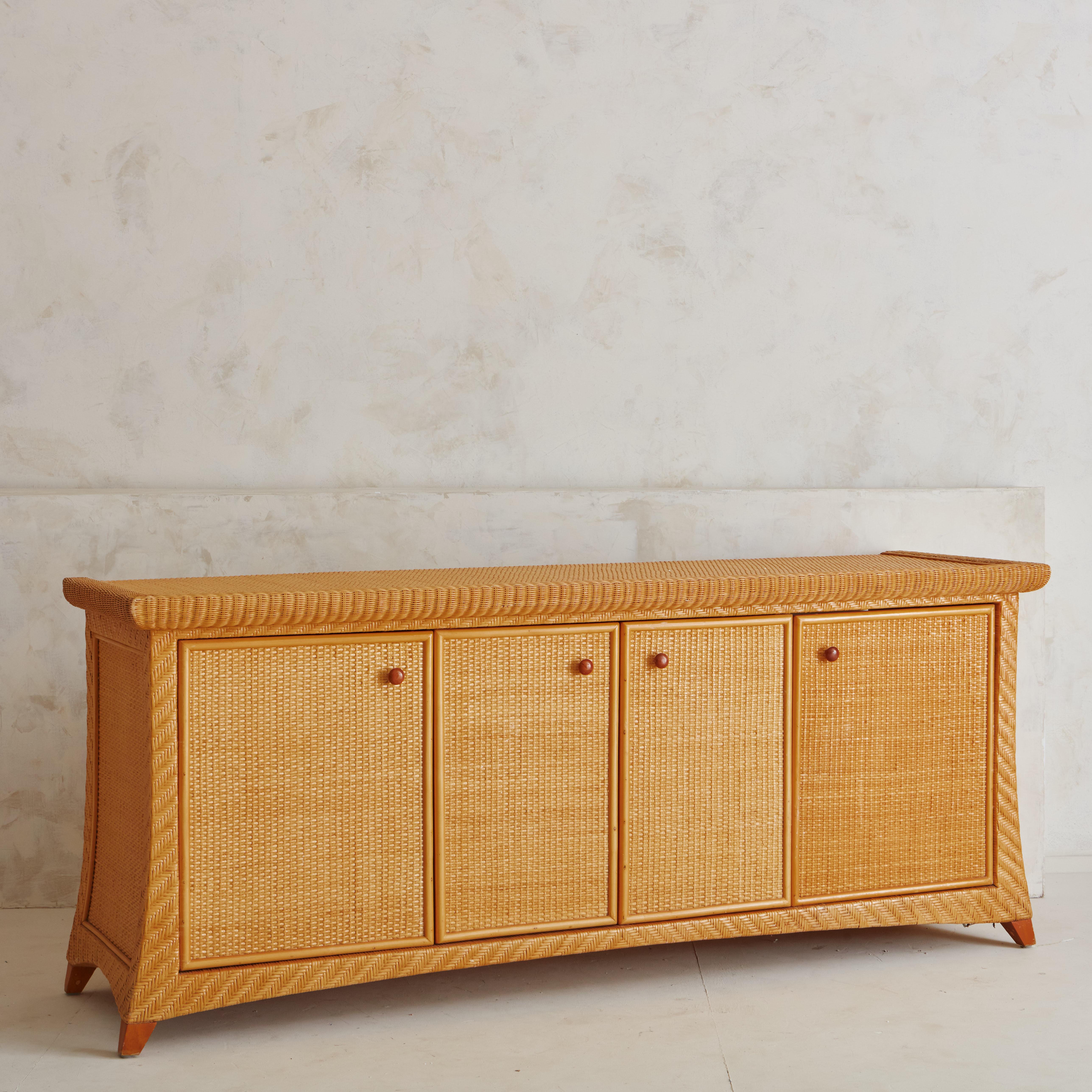 A gorgeous and uniquely shaped wicker credenza sourced from a home in the Mediterranean region of the Costa Brava, Spain. The wicker features warm honey tones and the shape of the credenza has a wonderful flair on each side. Two cabinet doors open