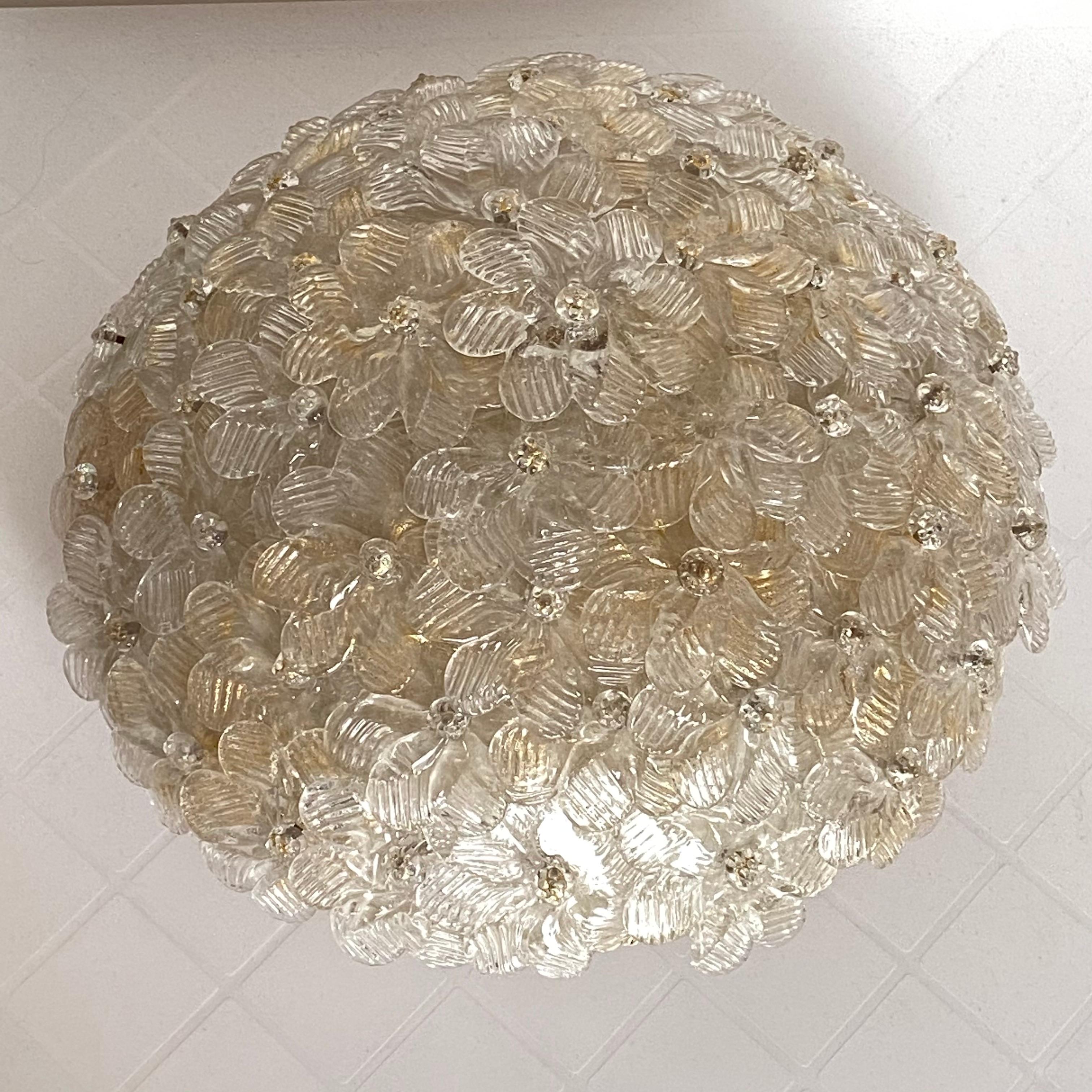 A hand blown Italian flush mount chandelier featuring overlapping crystal flowers, gold with 23-carat gold leaf fleck inclusions, mounted on a basket frame. The fixture requires three European E14 / 110 volt candelabra bulbs, each bulb up to 60