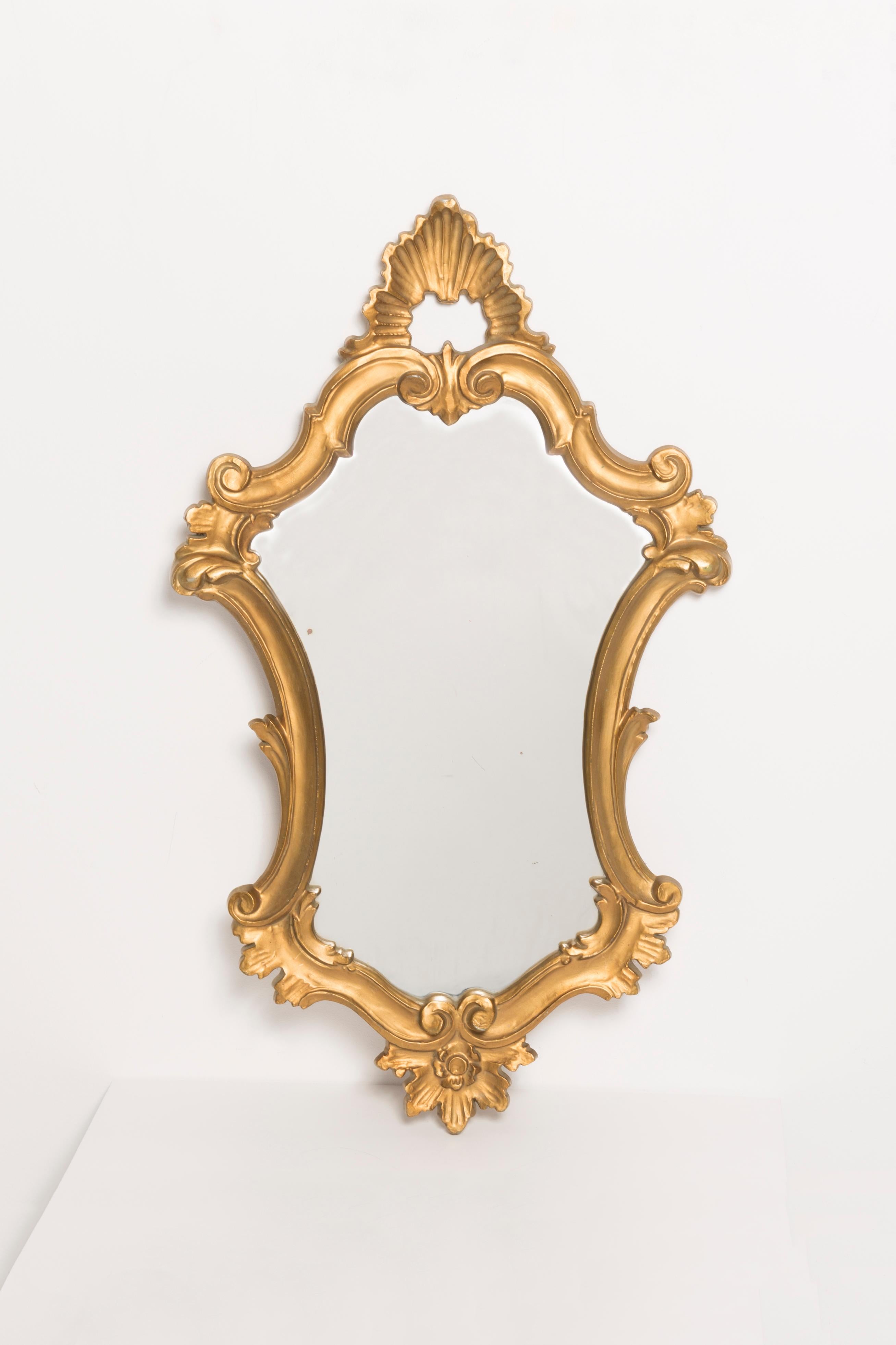 A beautiful medium mirror in a golden decorative frame with flowers. Produced in 1960s in Europe/Italy. The frame is made of wood, painted in gold wood paint. Mirror is in very good vintage condition, no damage or cracks in the frame. Original
