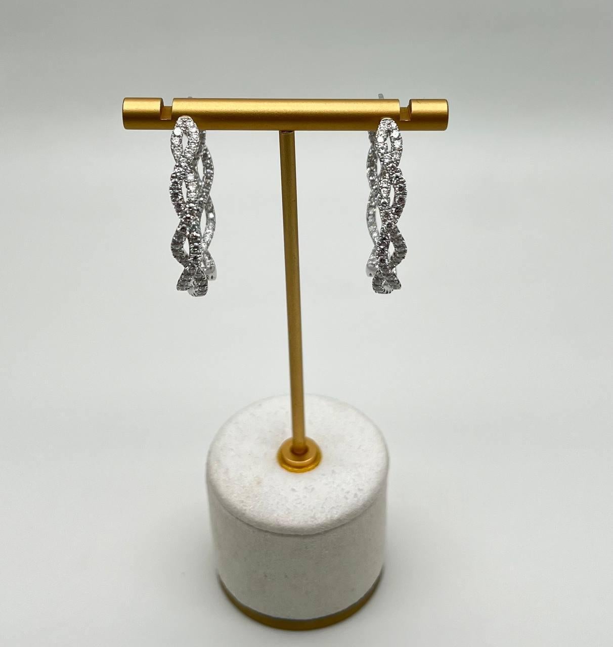 Uno splendido paio di orecchini, ciascuno realizzato in oro bianco, con un intricato disegno a tortiglione ornato da scintillanti diamanti a taglio rotondo. Le eleganti anse creano una silhouette accattivante, esaltando la brillantezza delle