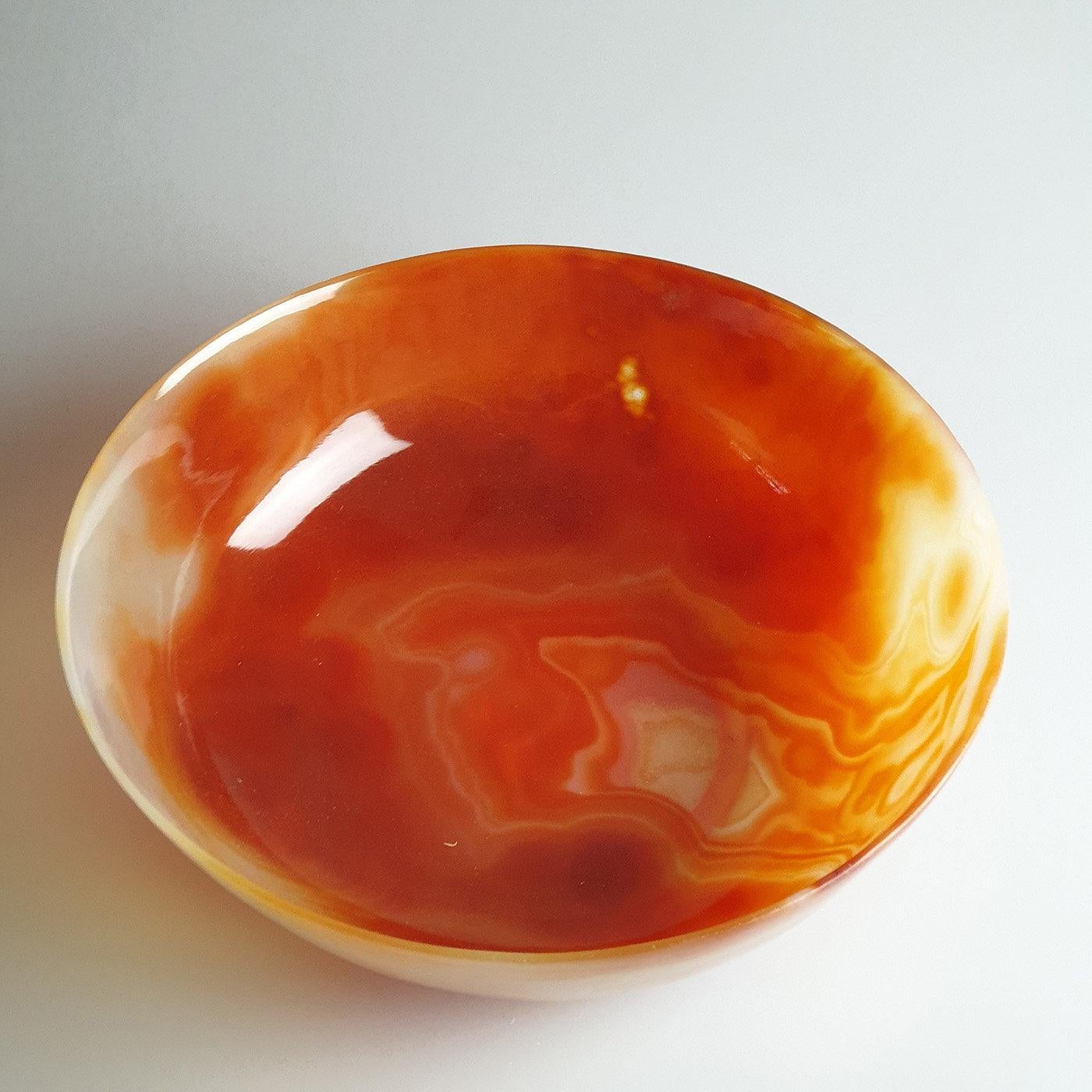 Boasting a dynamic and elegant interplay of colors, this bowl is manufactured from a single piece of the Brazilian carnelian agate. Ranging from a dark red to a rusty brown color, it features delicate shades that darken from the flared rim of the