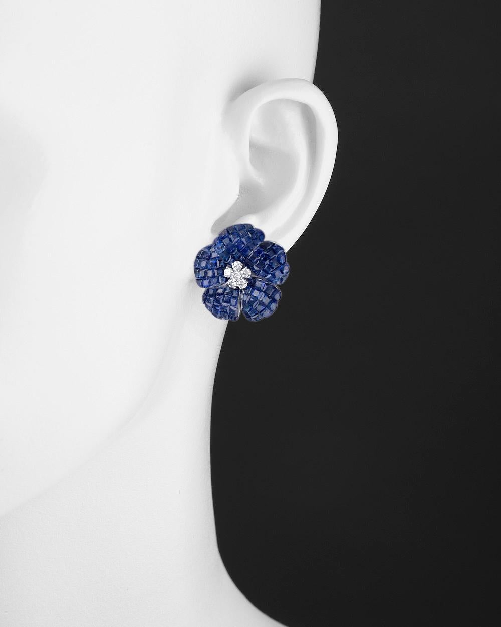 Flower earrings, designed as an invisibly-set calibre-cut sapphire flowerhead centering a cluster of round-cut diamonds, mounted in polished 18k white gold.

Sapphires weighing 25.23 total carats
Twelve diamonds weighing 0.48 total carats
Clip backs