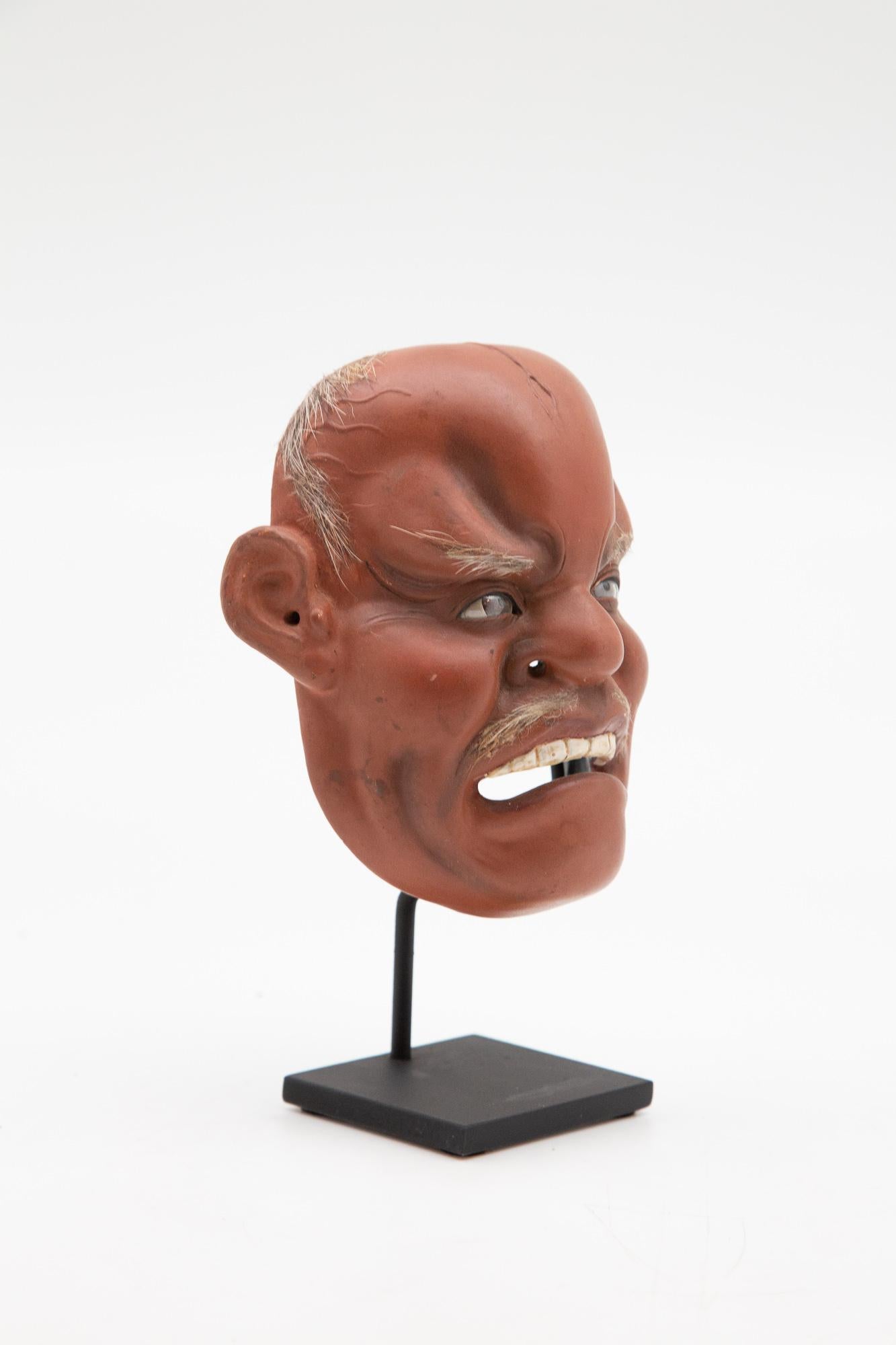 Medium Japanese Papier-Mâché (19th Century) Iki Ningyo mask or sometimes referred to as Noh mask, mounted on custom painted metal base.  Trimmed with natural hair and glass, painted glass eyes.