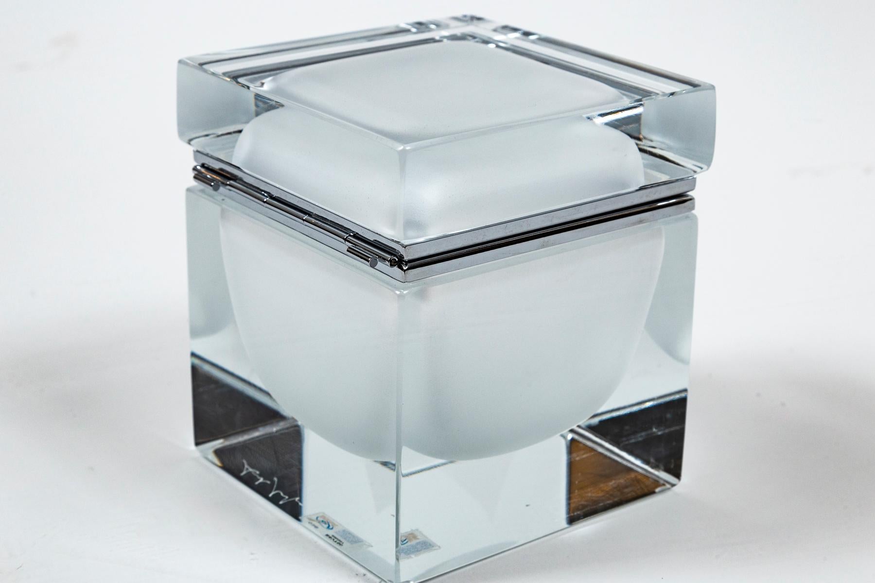 Eine von einer Art Murano handgefertigte mittelgroße quadratische Dose aus klarem mundgeblasenem Glas mit einer schwebenden mattierten weißen Kugel in der Mitte, individuelle Größe für jede Dose mit Nickel auf Messingbeschlägen.
Die Schachteln sind