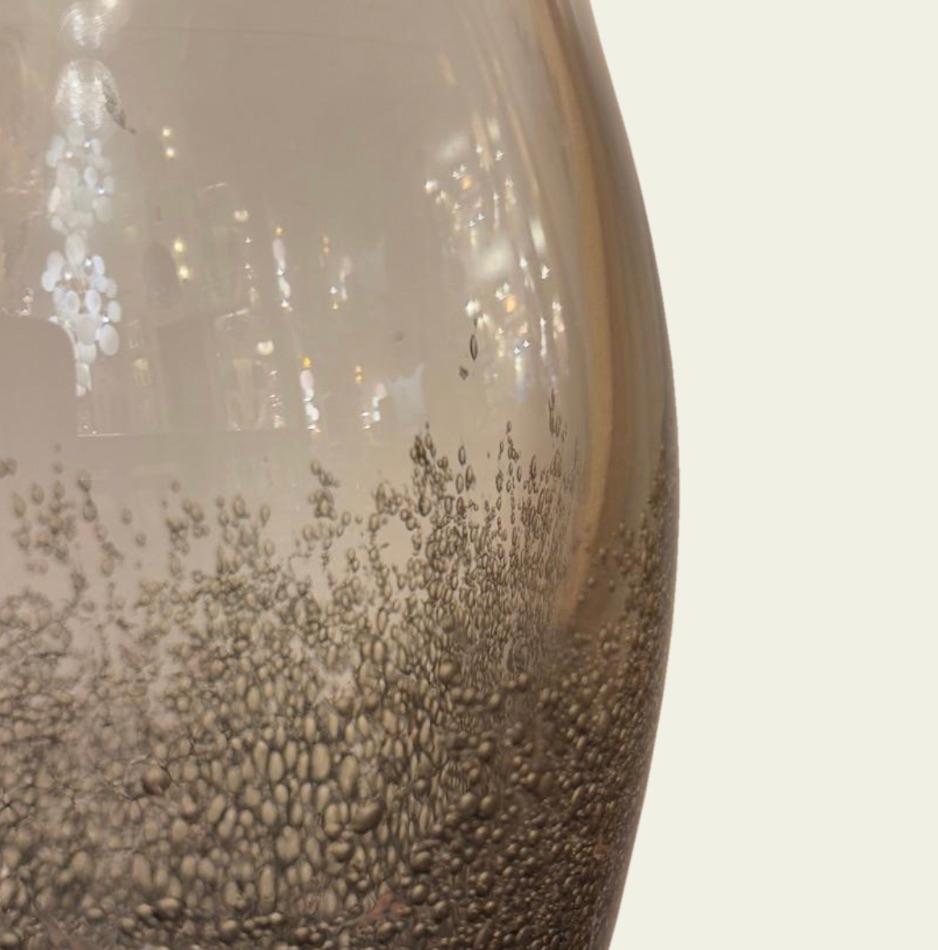 Mit ihrer rauchigen, grauen Farbe und der sprudelnden Textur bringt diese Glasvase die Eleganz venezianischer Handwerkskunst in jeden Raum. Diese Vase wurde in Murano in der traditionellen Pulegoso-Technik mundgeblasen und weist eine dichte