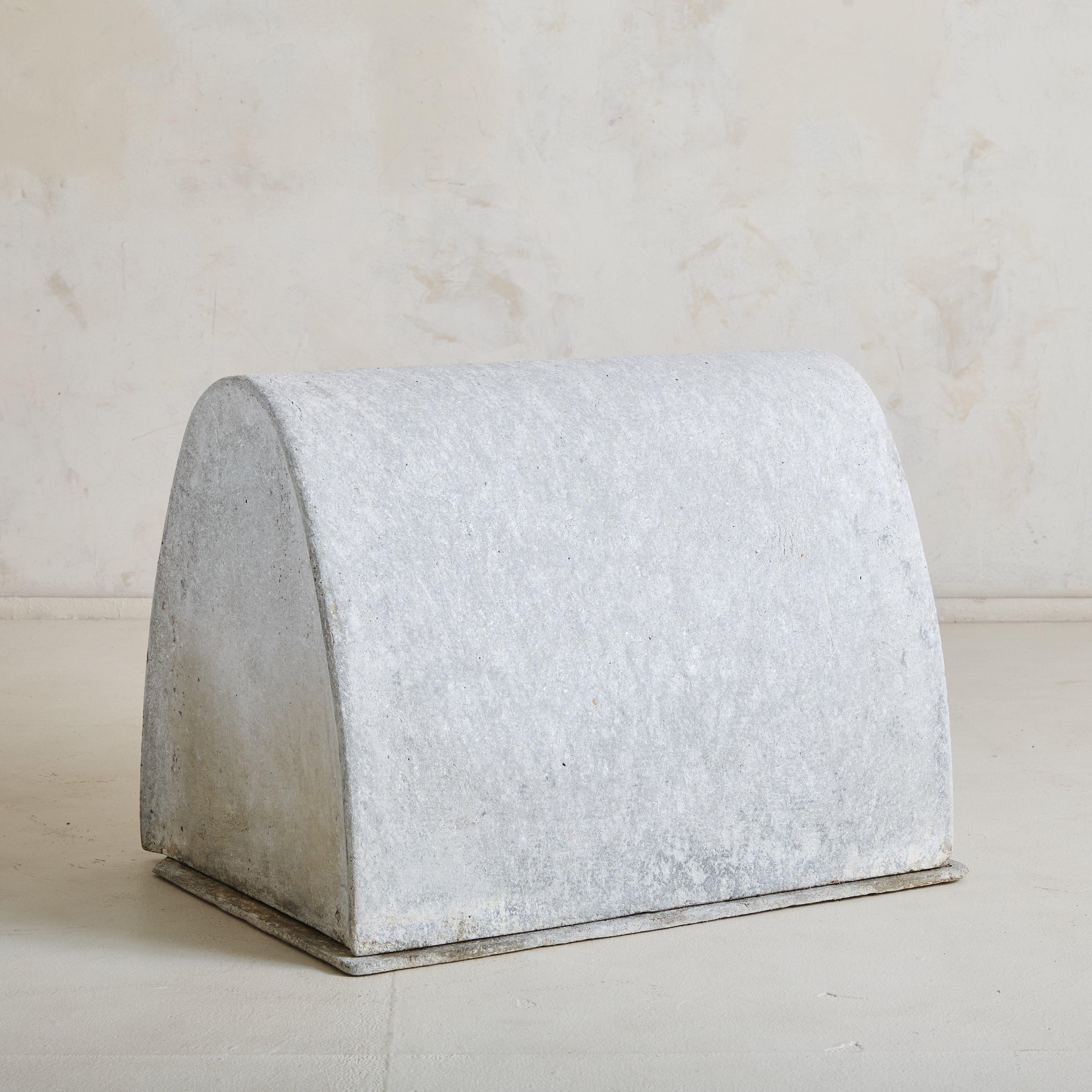 A rare 1960s concrete dog house designed by renowned Swiss designer Willy Guhl. The structure features a simple elongated base topped by a raised semicircular arch that peaks at a delicate crest, with an opening positioned on the left. Over time, it