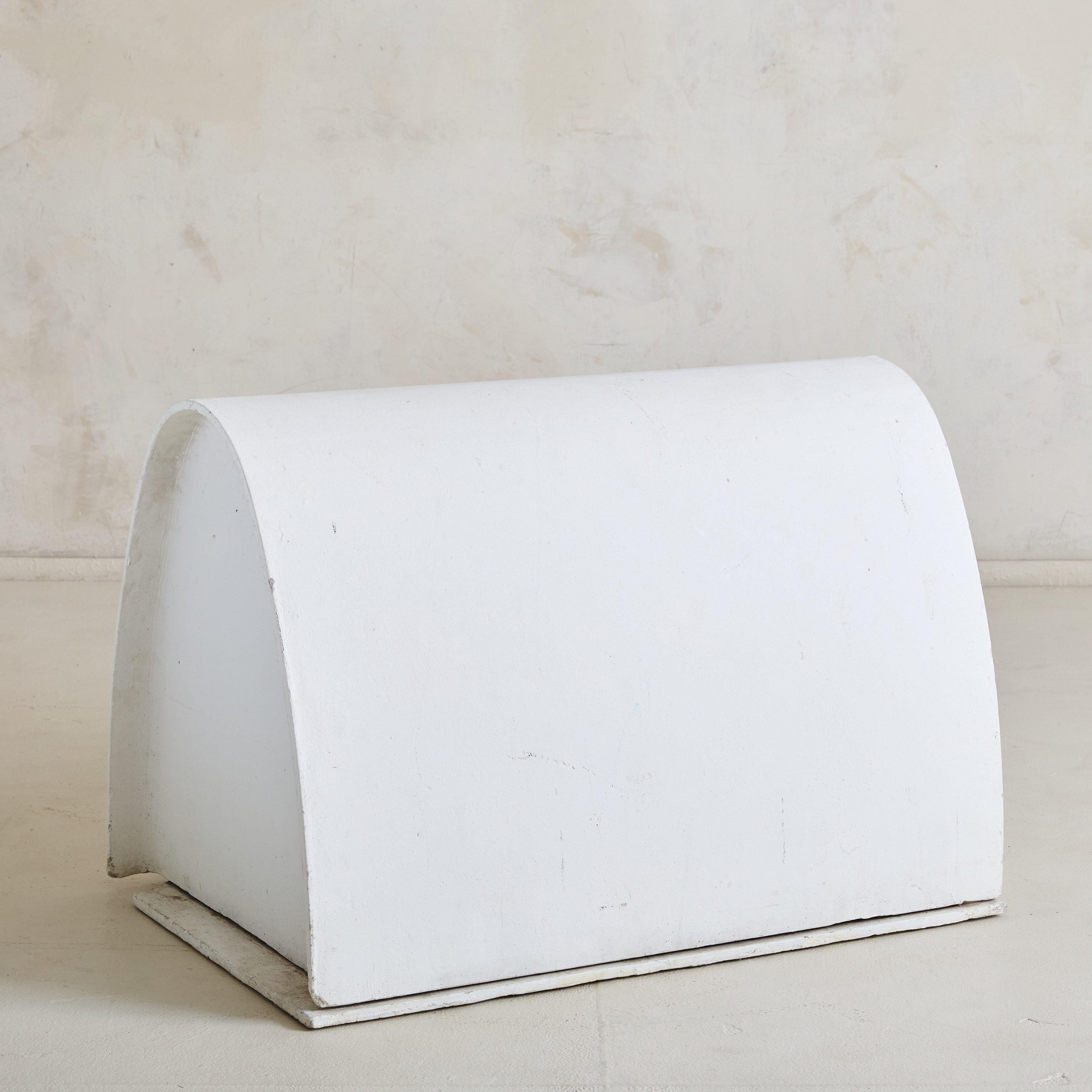A rare 1960s concrete dog house designed by renowned Swiss designer Willy Guhl. The structure features a simple elongated base topped by a raised semicircular arch that peaks at a delicate crest, with an opening positioned on the left. Over time, it