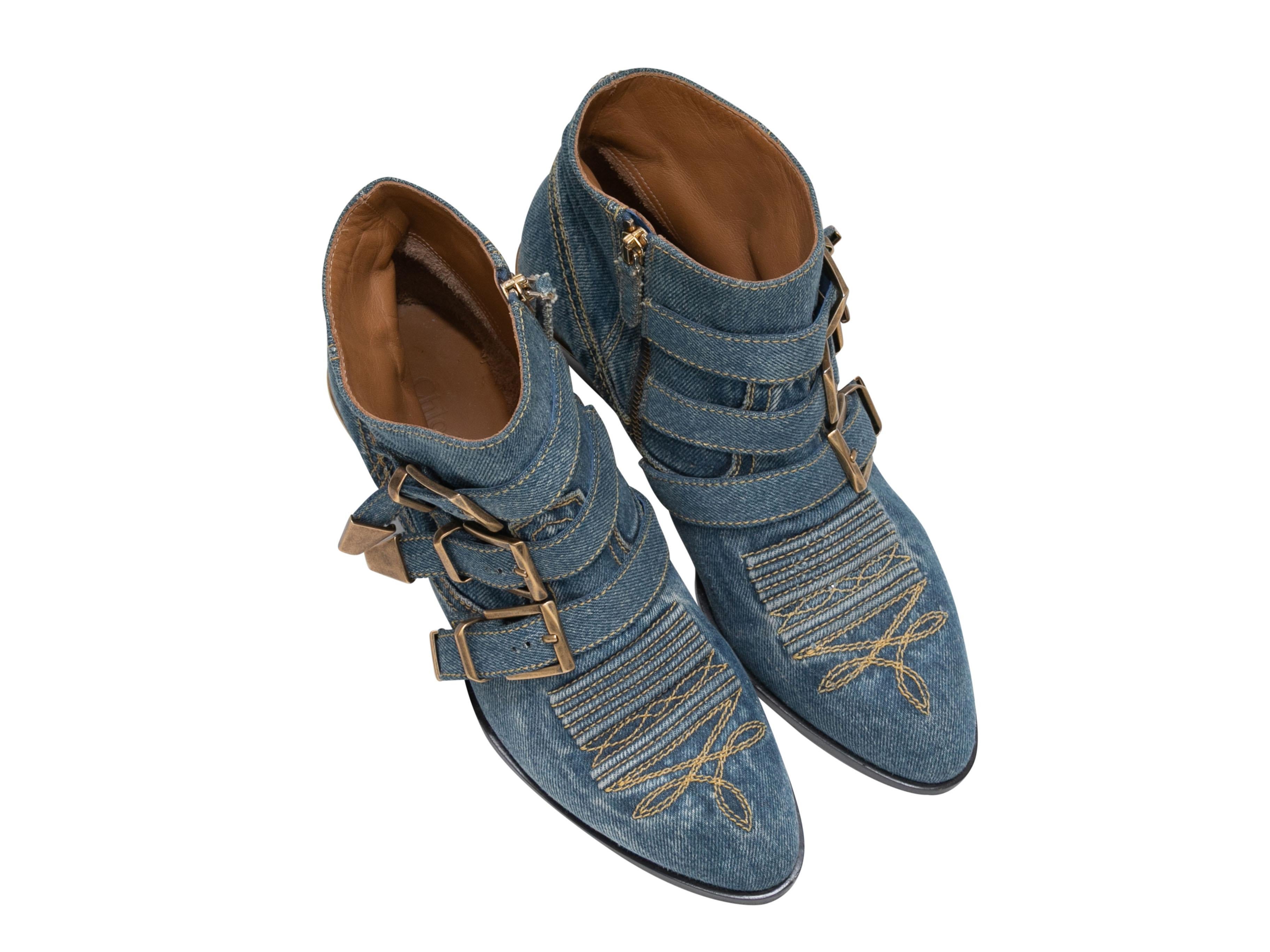 Medium wash denim western ankle boots by Chloe. Gold-tone hardware. Buckle accents at tops. Zip closures at inner sides. 5