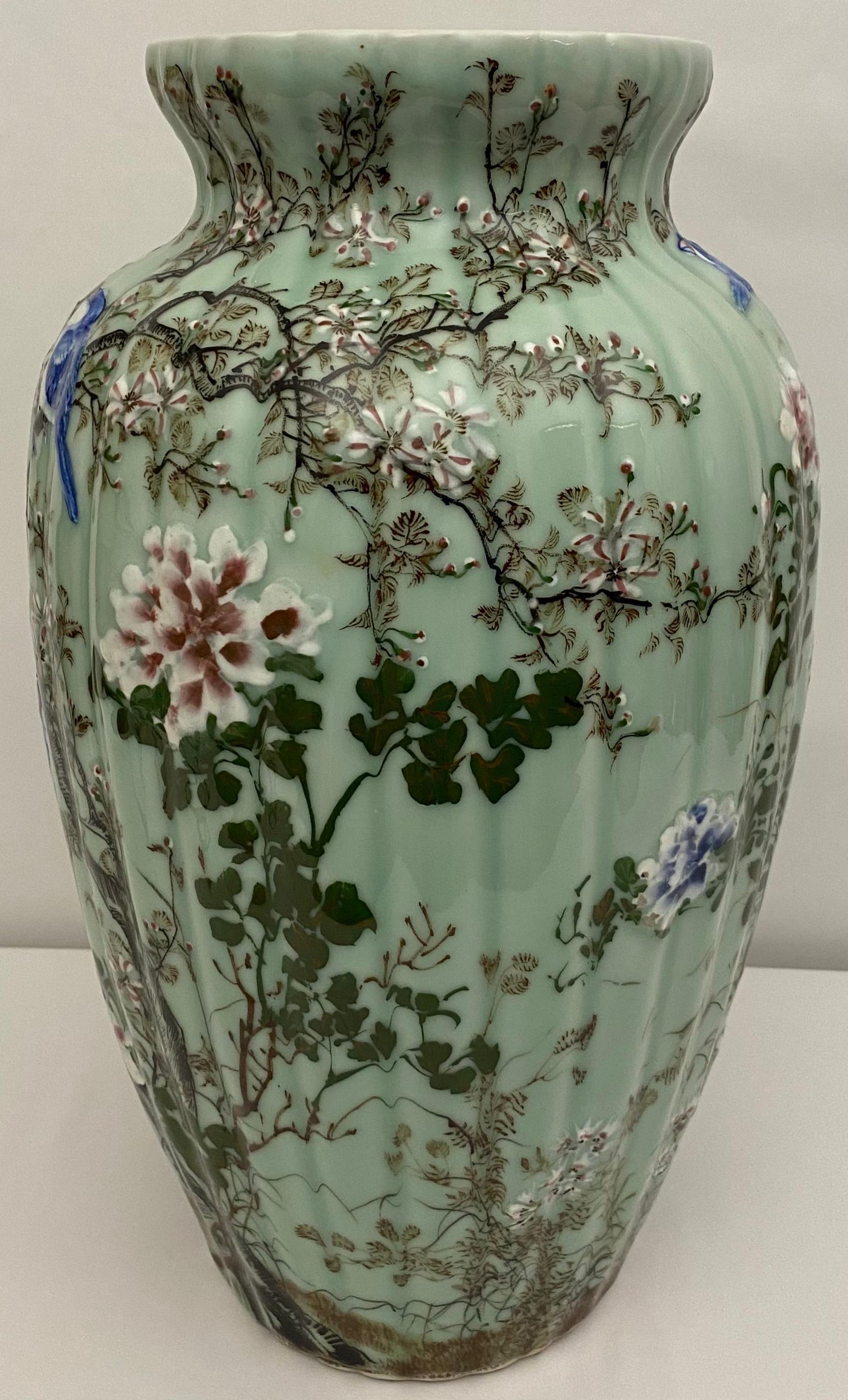 This captivating Medji period (1868-1912) porcelain vase features a mesmerizing celadon glaze, with a subtle crackled texture. Exquisite details, meticulously hand-painted in vibrant blue, white, greens, and pale pink enamels, adorn the surface in