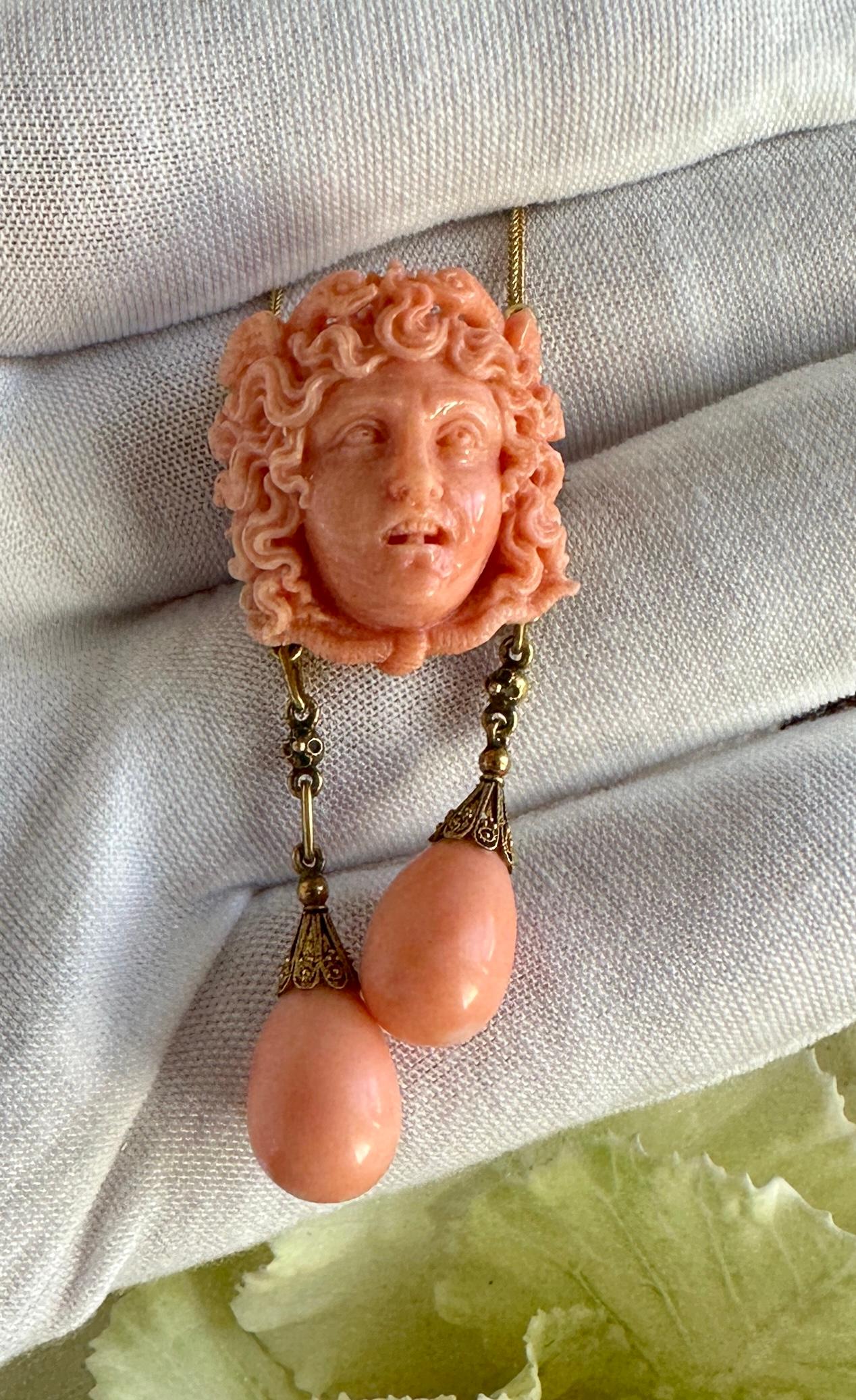 This is a Museum Quality Antique Etruscan Revival Victorian Carved Coral Necklace depicting Medusa with a Crown of Snakes with two pear shape coral drop pendants.  The Coral Medusa is set in 14-18 Karat Gold with extraordinary Etruscan Revival