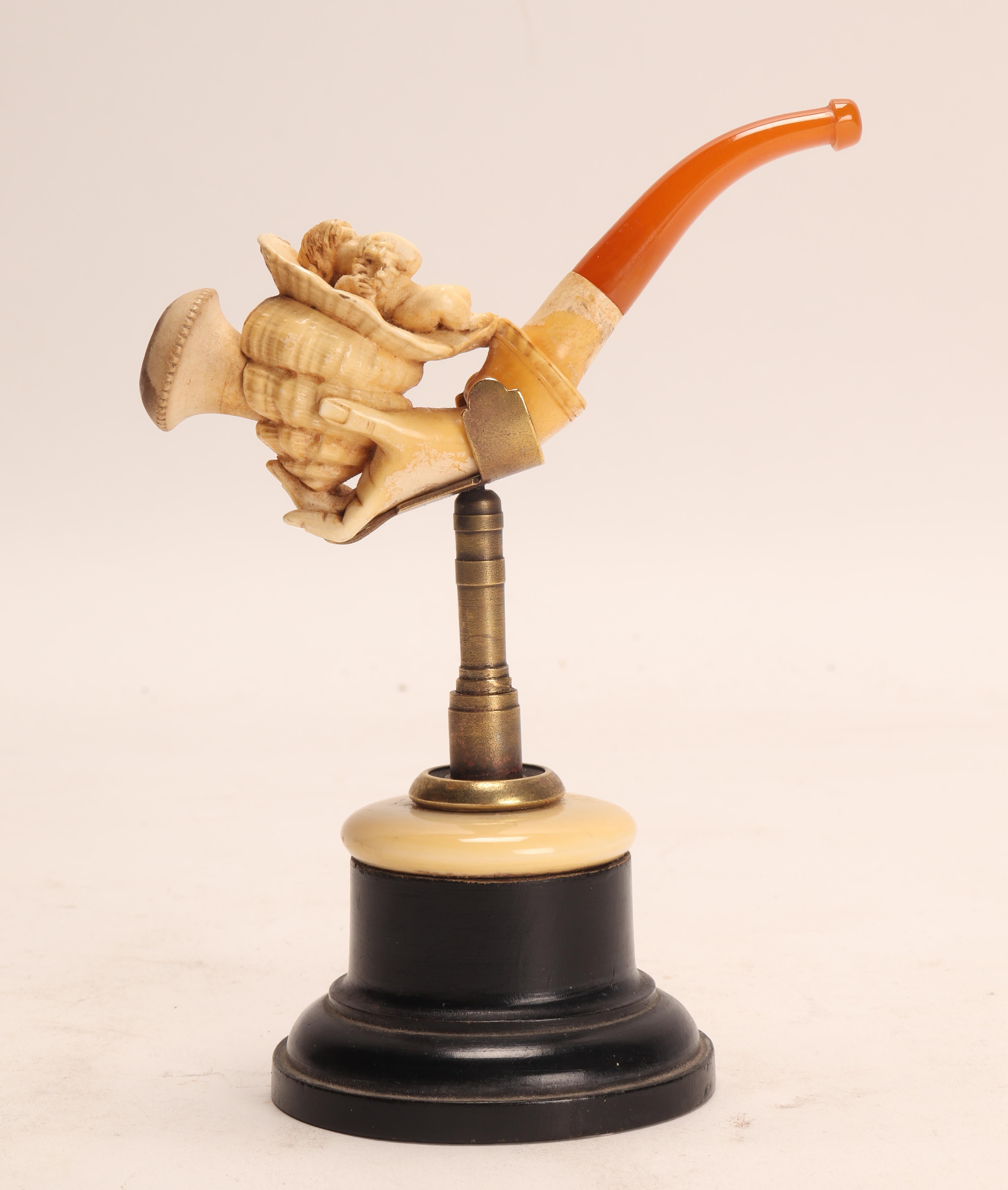 Tobacco taster pipe, made out of carved meershaum, with amber mouthpiece. One hand holds a cornucopia with Cupid. Vienna, Austria circa 1890.  (The stand is for photographic use only, not for sale).