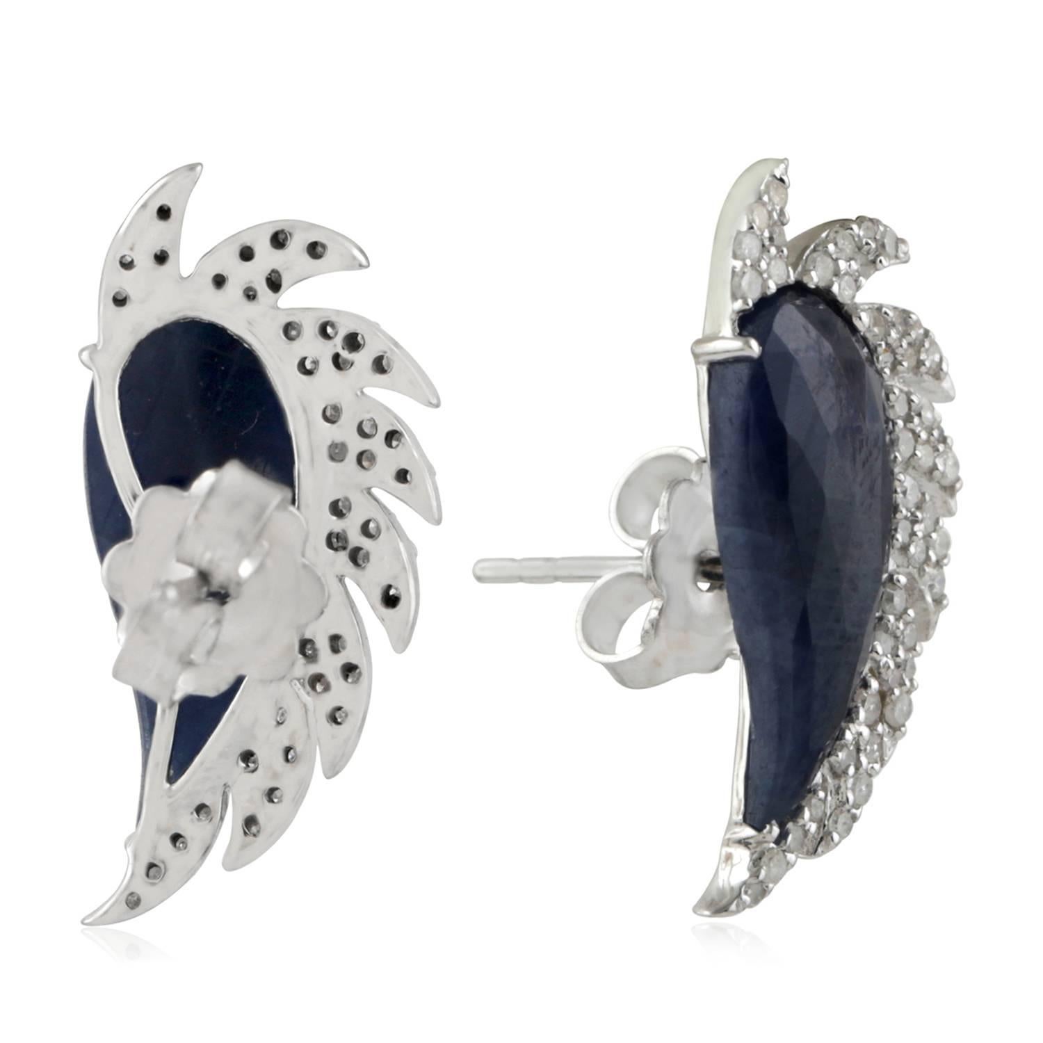These distinctive stud earrings are modern twist to fine jewelry, handcrafted in 14K gold, sterling silver, blue sapphire and diamonds. The iridescent 16.0-ct rose cut blue sapphire is surrounded by 0.67-ct signature diamond pave arches. A fusion