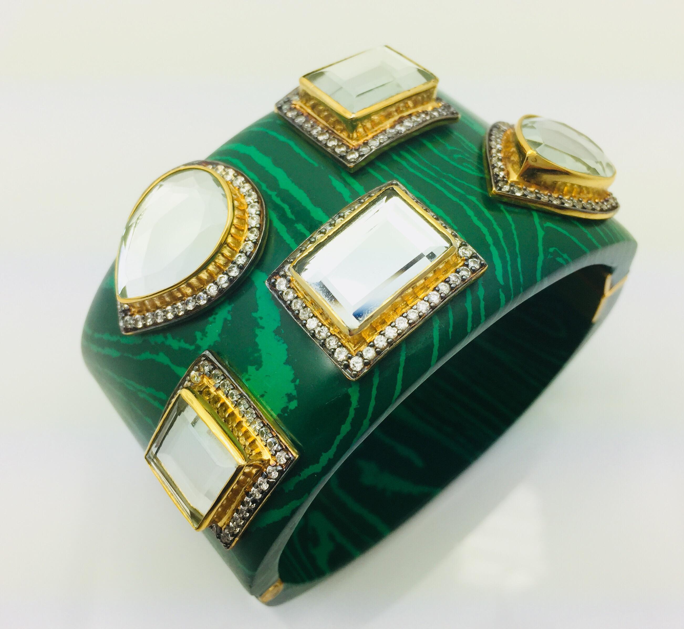 The smooth malachite resin bracelet provides a stunning backdrop for the various shapes of light reflective mirror stones, each of which has its own frame of dazzling CZs. Bracelet has a hinged, box tab closure.

Available in Black Onyx and