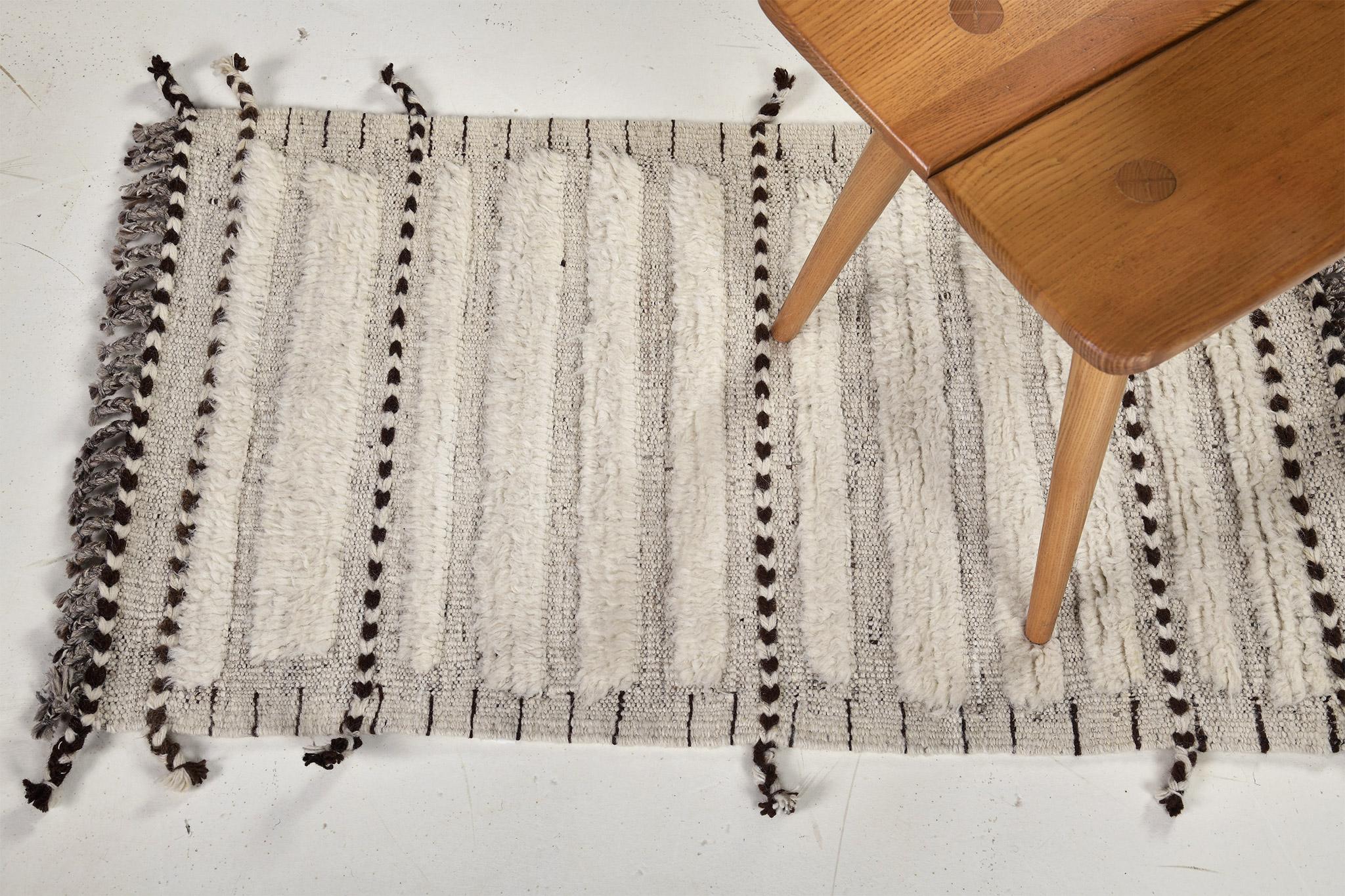 Abrolhos es una lujosa alfombra de lana tejida a mano con detalles en relieve atemporales. Además de su perfecto tejido plano marfil y gris, Albrohos tiene un precioso shag que aporta una textura lustrosa y un aire contemporáneo a tu espacio. La