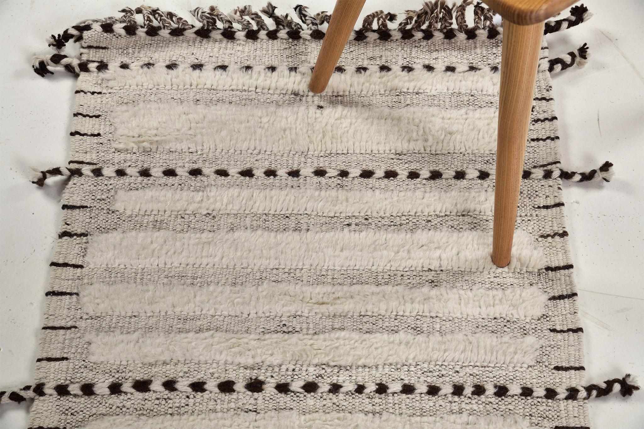 Abrolhos is a handwoven luxurious wool rug with timeless embossed detailing. In addition to its perfect ivory and gray flatweave, Albrohos has a beautiful shag that brings a lustrous texture and contemporary feel to one's space. The Haute Bohemian