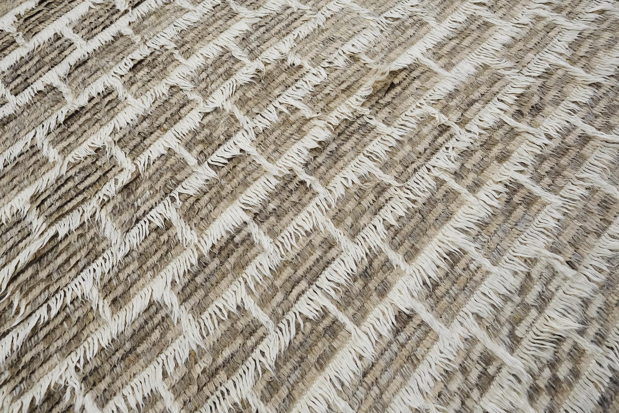 In the Ahina rug, a rectangular grid frames a field of dappled pile tones. This piece combines ivory lines with heathered clay and taupe tones. 

Hand knotted of hand-spun wool, the Sahara Collection melds linear organization with a relaxed
