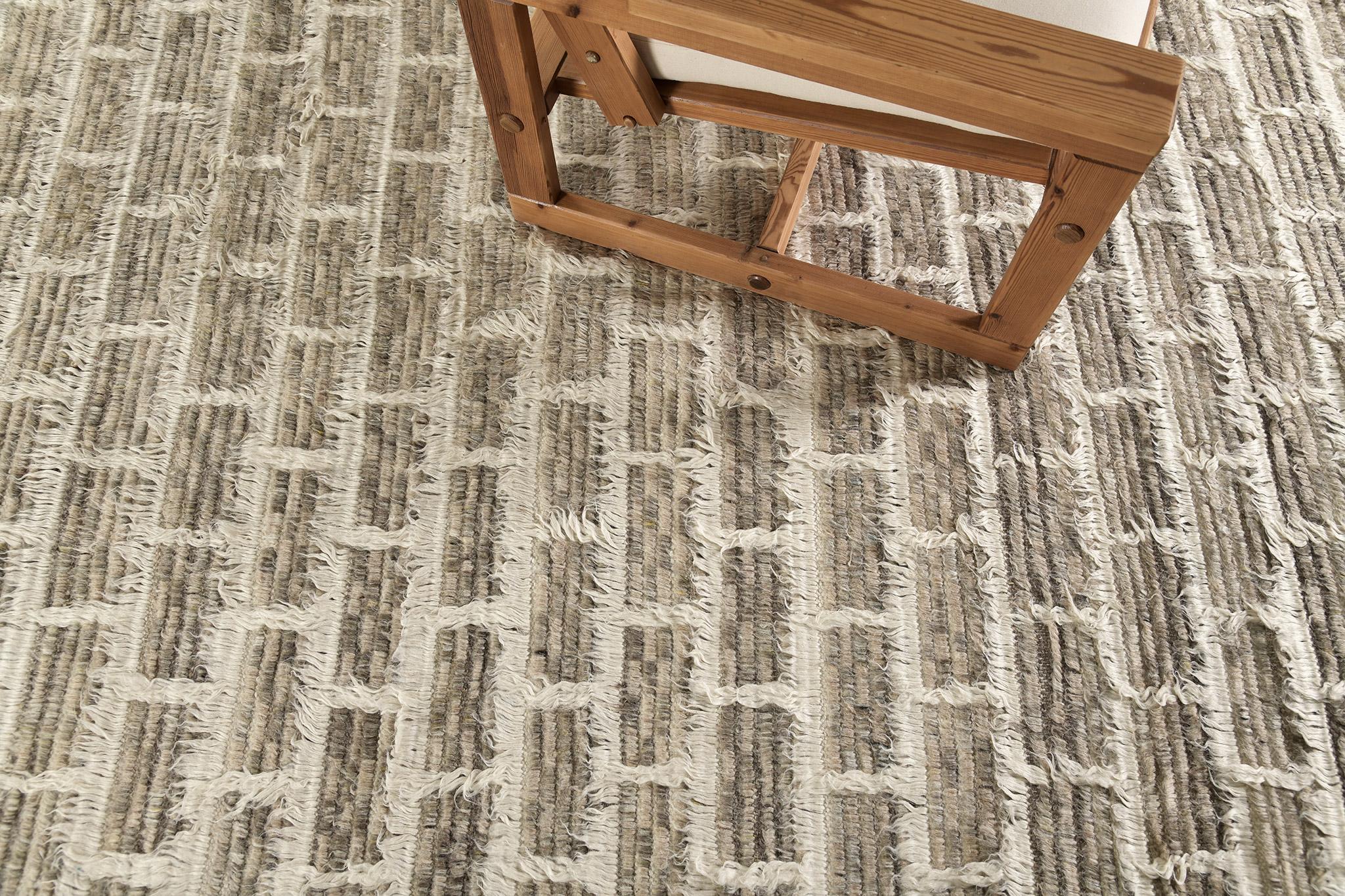 In the Ahina rug, a rectangular grid frames a field of dappled pile tones. This piece combines ivory lines with heathered clay and taupe tones. 

Hand knotted of hand-spun wool, the Sahara Collection melds linear organization with a relaxed organic