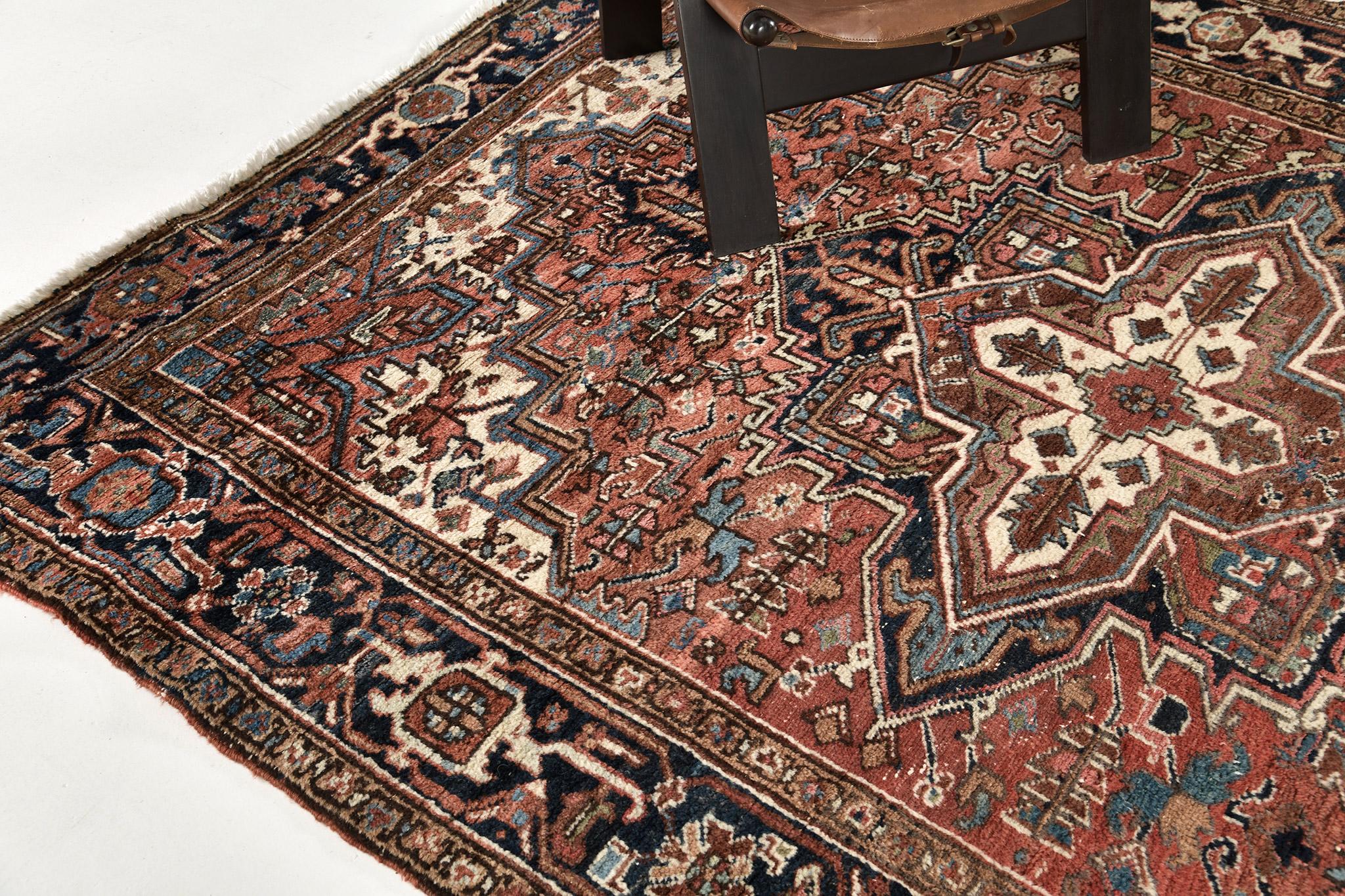 Dieser faszinierende antike persische Heriz-Teppich zeichnet sich durch eine rustikale Farbmischung aus. Es zeichnet sich durch ein kompliziertes Design und Details aus, die ein botanisches Medaillon hervorheben, das die Aufmerksamkeit des