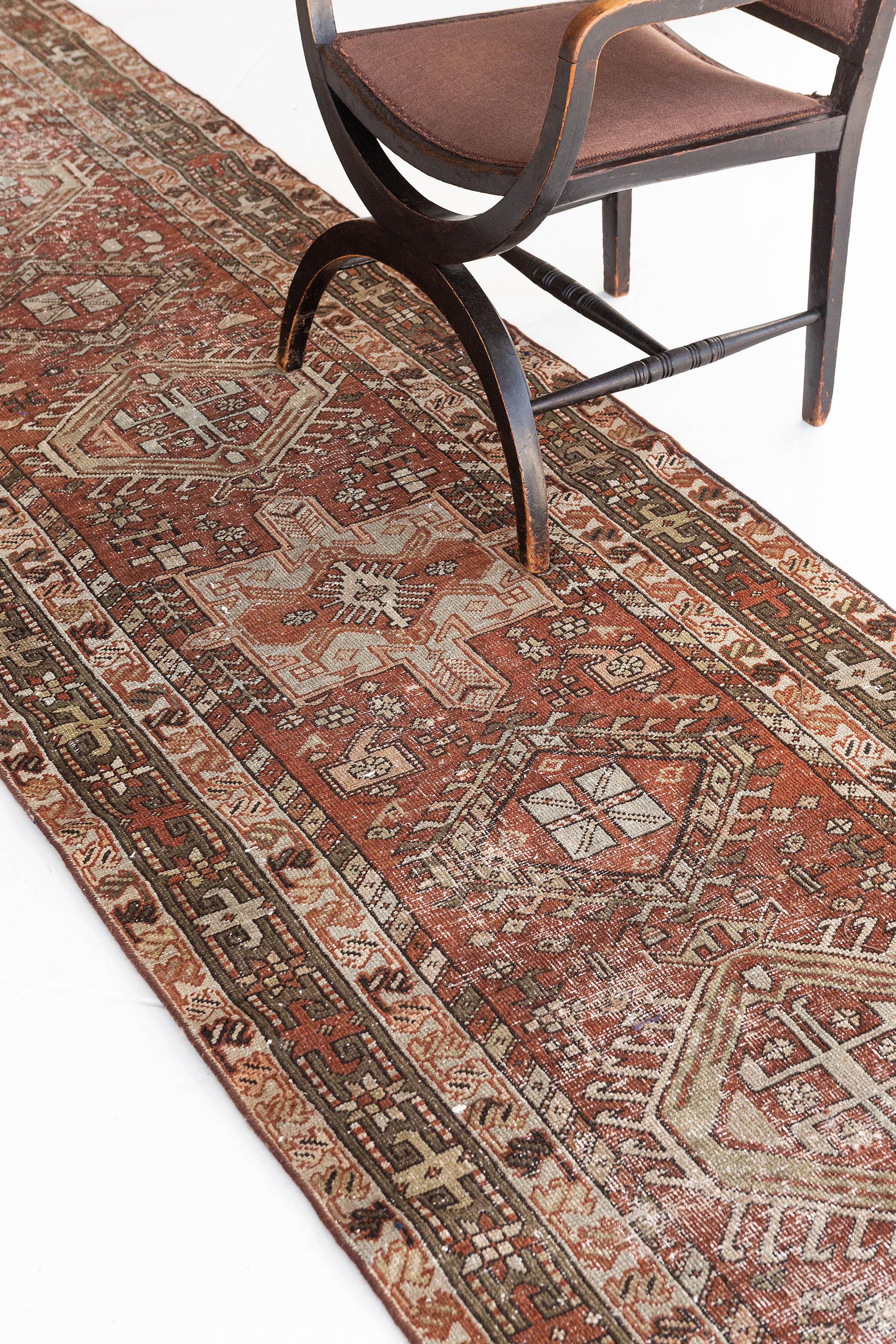 This chic antique Persian Heriz runner rug is a robust red and rust blend of colours. It is distinguished by its beautiful lines and details featuring various medallions lining up together to create a fascinating piece that will surely captivate the