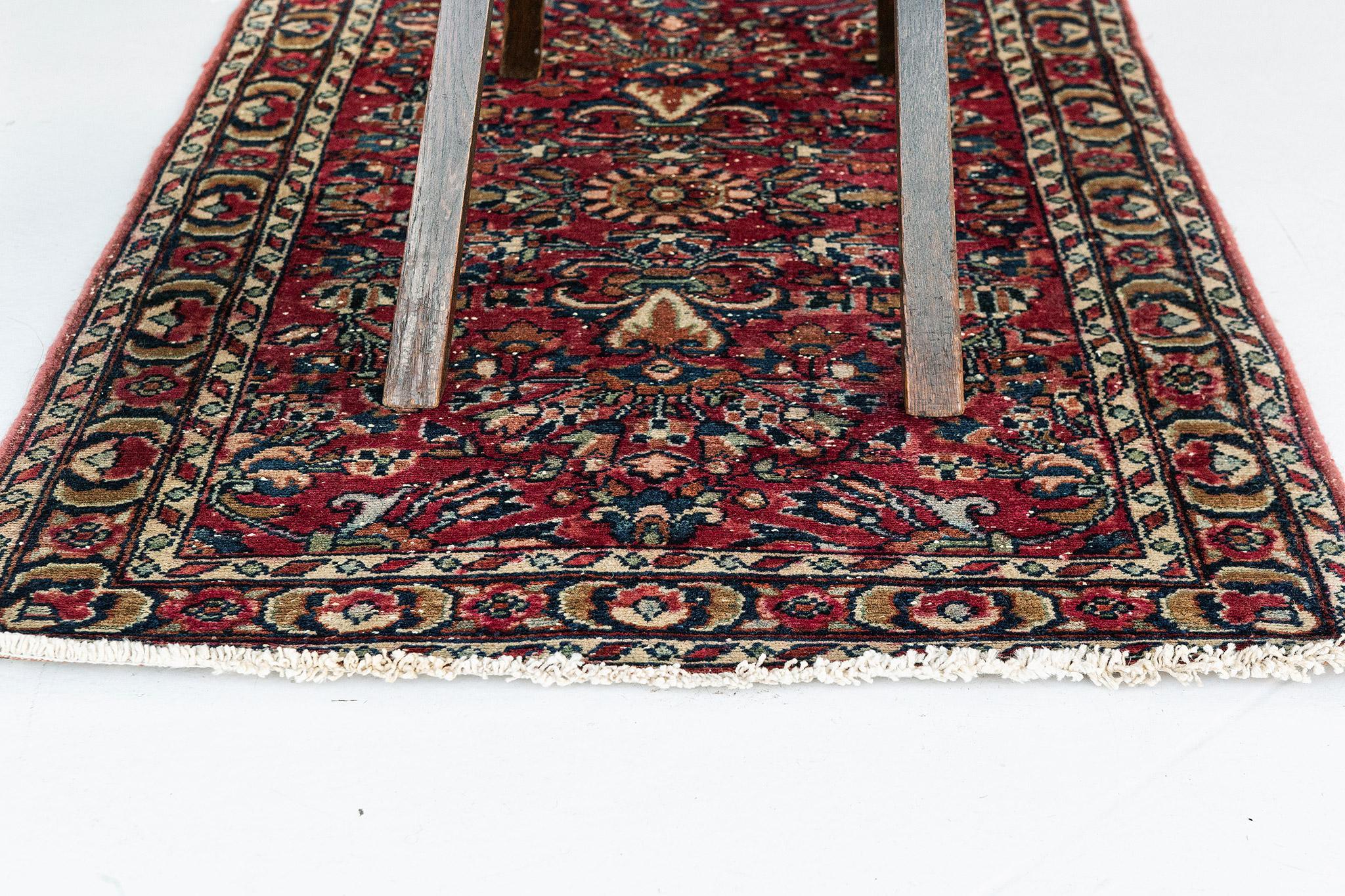 A magnificent antique Persian Lilian rug that emanates a balanced and timeless floral design with a lovingly timeworn patina. The abrashed scarlet field is covered with an all-over botanical pattern composed of blooming palmettes, serrated leaves,