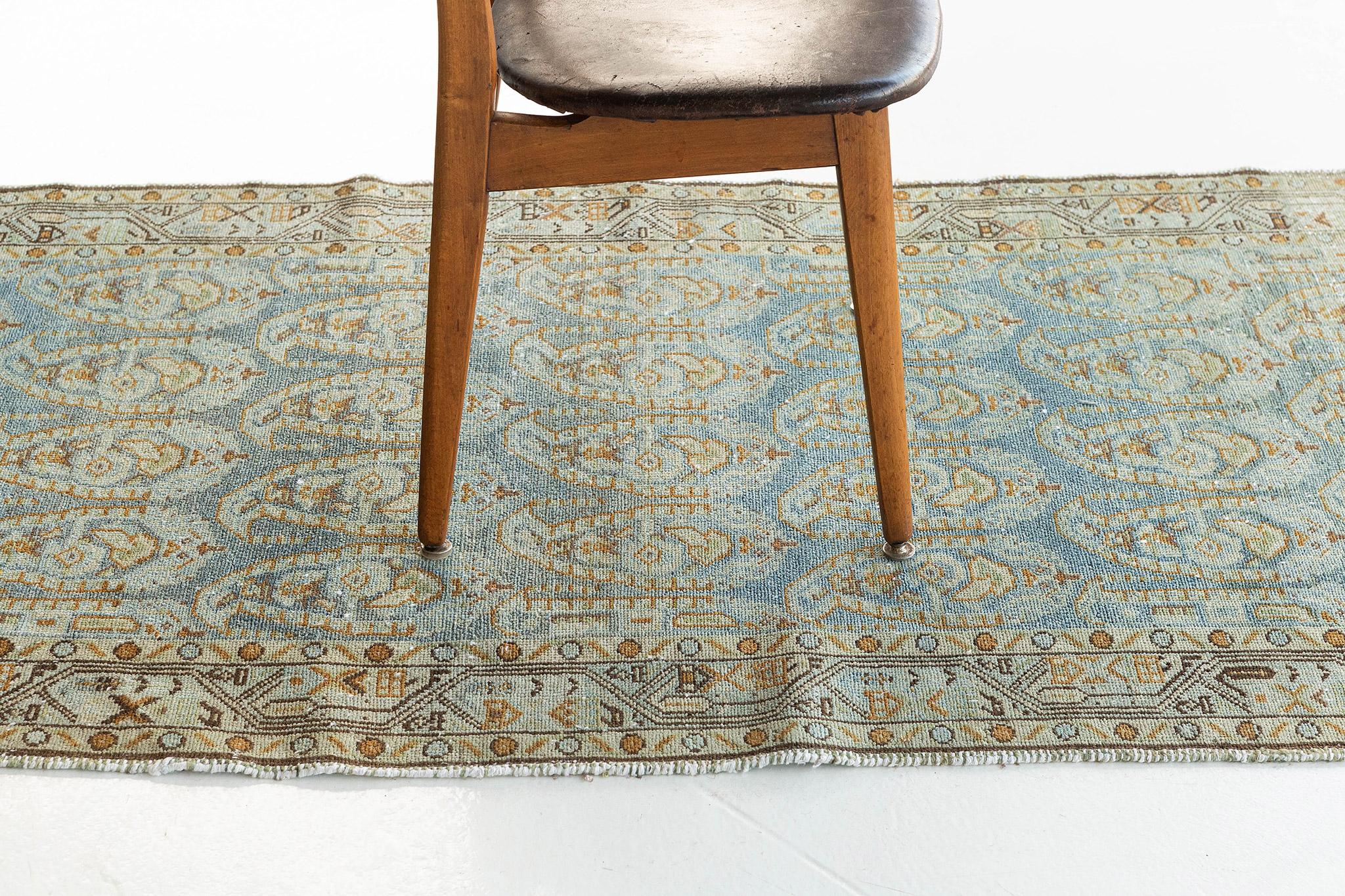 A majestic Antique Persian Malayer Runner that features a dynamic all-over florid elements cusped in boteh motifs gracefully flourishing an abrashed azure field. Enclosed by golden and cinnamon brown borders composed of floral meander guard band,