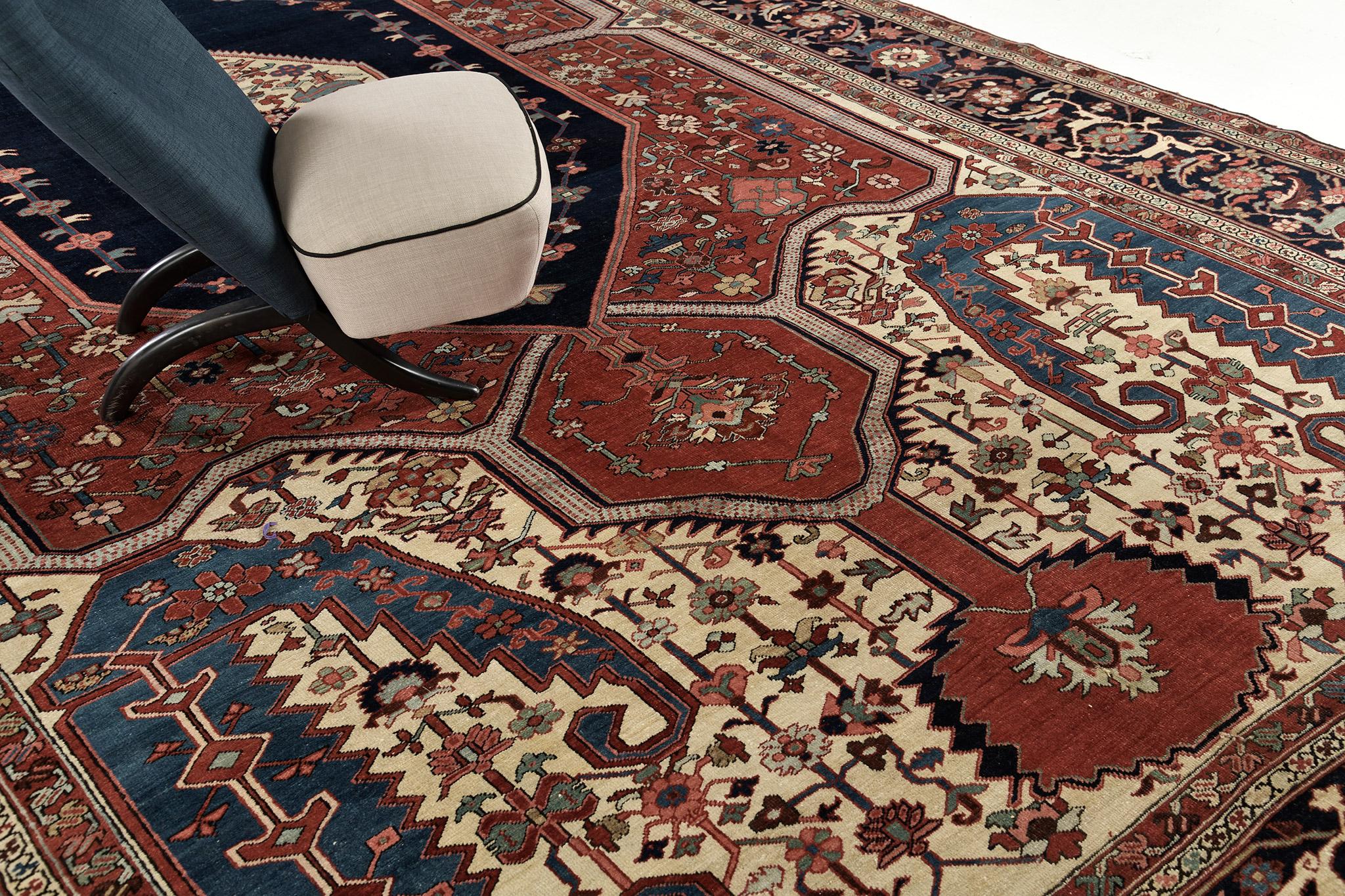 Our stunning Serapi rug features beautiful hues that are accented by a midnight blue central medallion. Majestically ensembled leafy scrolls, blooming florets, and motifs are well-coordinated with the brick red and night blue color schemes. A decor