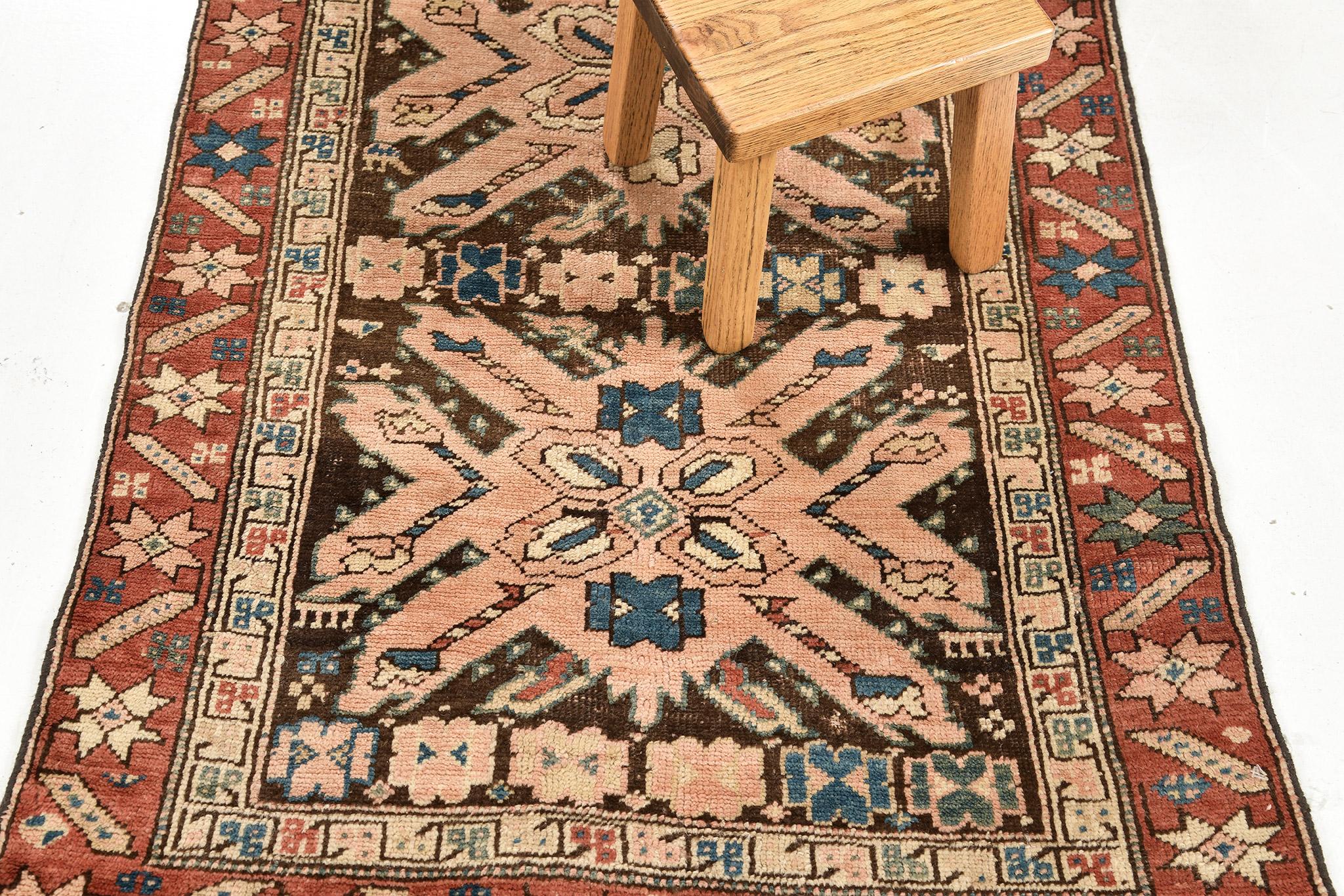 This genuine antique Russian Gharabagh rug is a beautiful runner piece styled in the tribal design out of wool using the pile weave method. The multicolored rug is framed by a blushing lattice border. Come by our design studio for more luxury rug