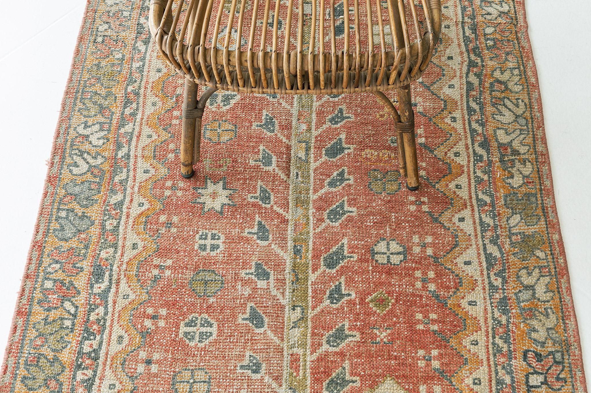 A vigorous Gordes design rug runner that stars the majestic tones of terracotta, gold, and ivory. The abrash field is covered with an all-over pattern composed of tulip sprigs, blooming palmettes, sickle leaves, stylized florals, and leafy tendrils.