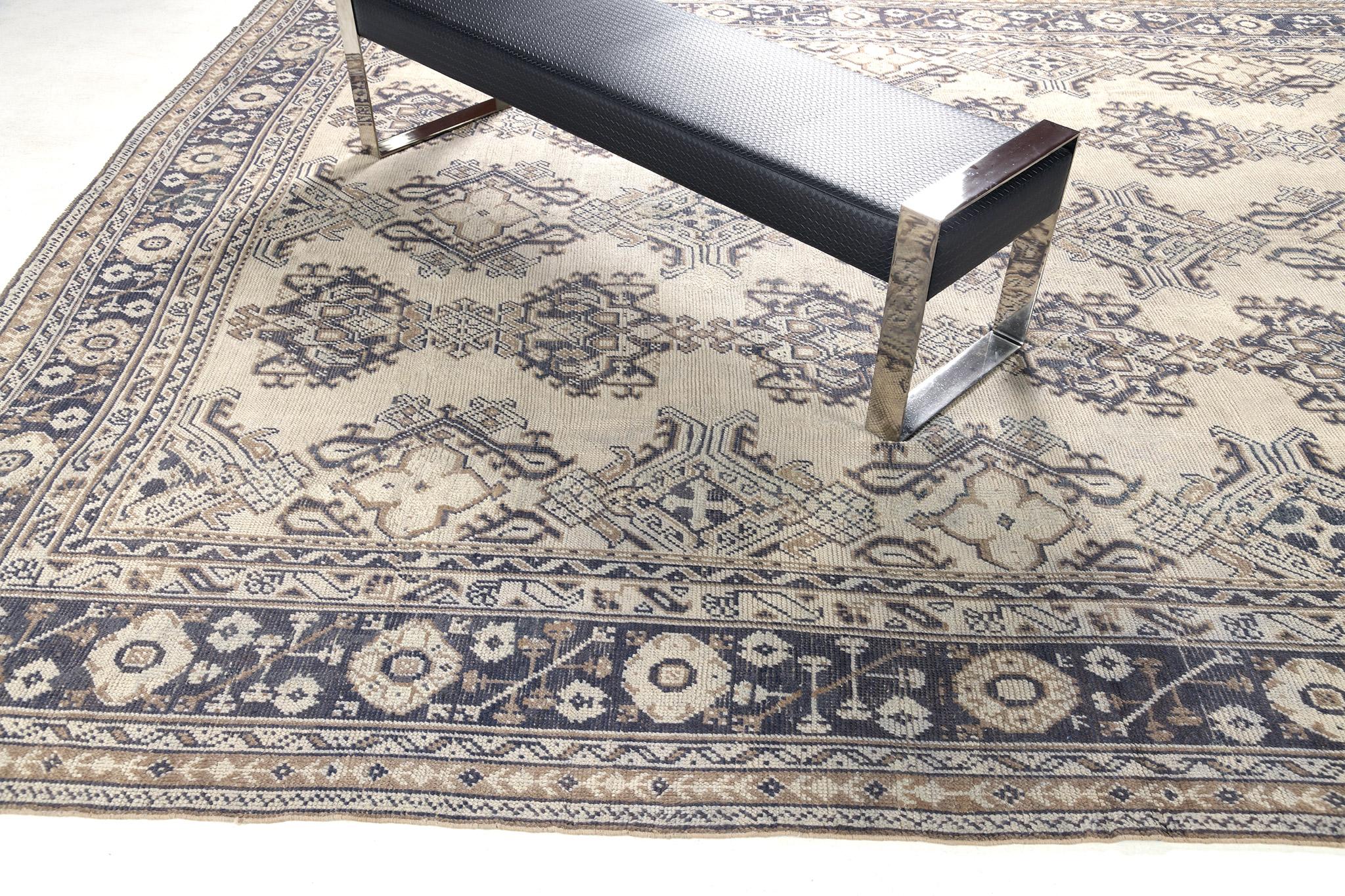 A stylish Oushak revival rug in the muted tones of ivory and aegean blue stylized gracefully with allover medallion patterns. Classic and sophisticated, this rug from hand spun wool is framed by a complementary border filled with elements that form