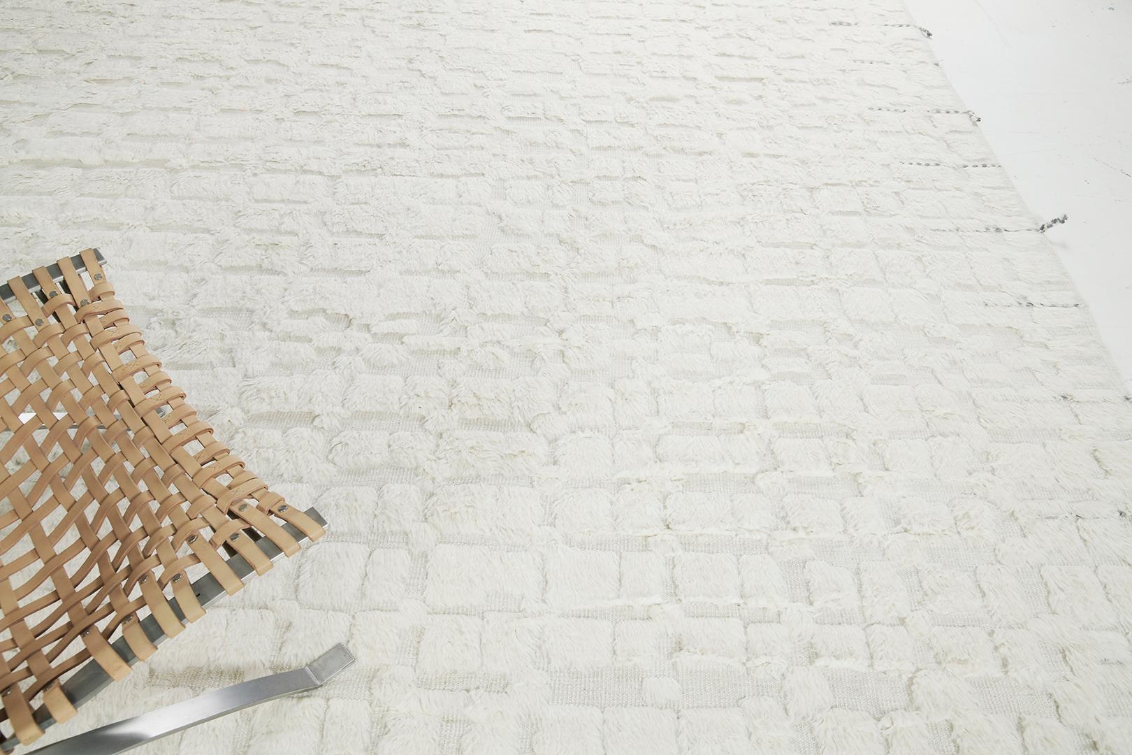 Anzade' est un tapis époustouflant de notre collection Atlas qui présente un champ gris clair en peluche qui incite le spectateur à enfoncer ses pieds dans son tissage ivoire gaufré. Accentué par des motifs carrés gris inégaux qui rendent ce tapis